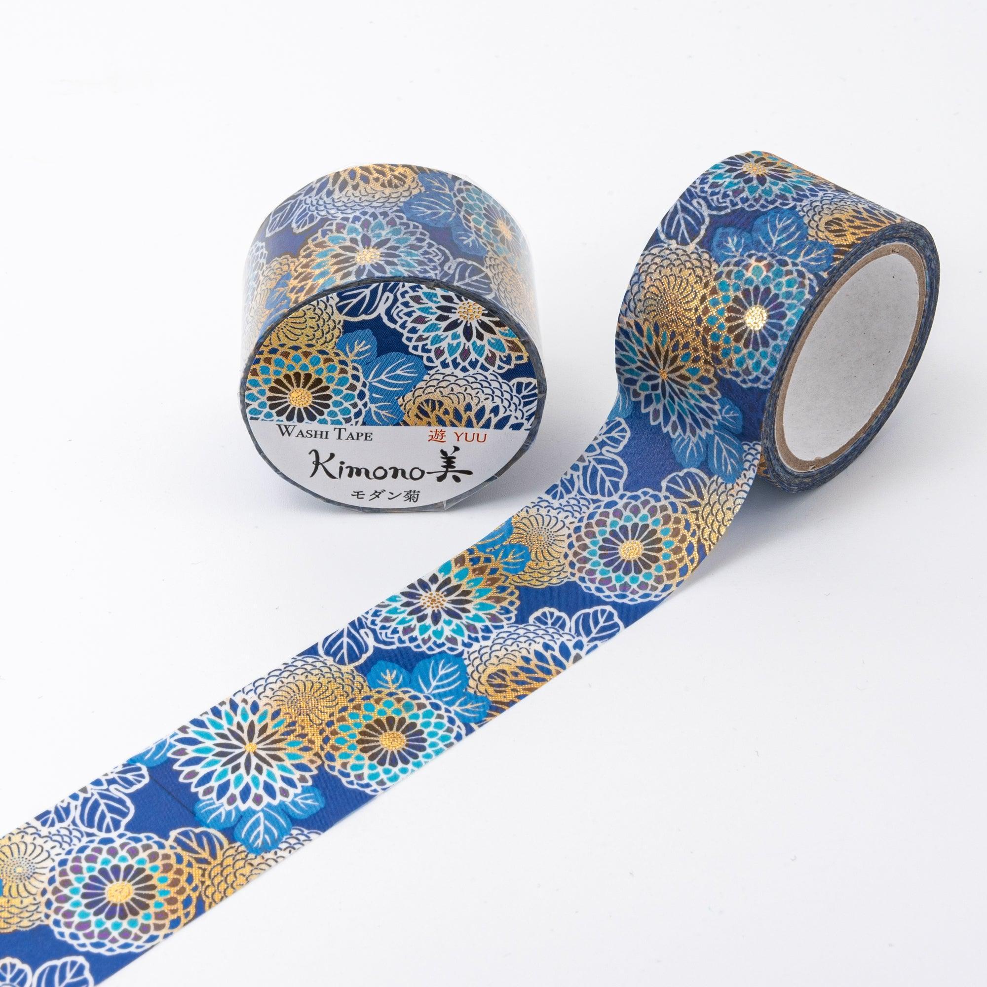 Close-up of Japanese stationery washi tape with golden chrysanthemum patterns, white accents, and blue detailing on a navy blue base.
