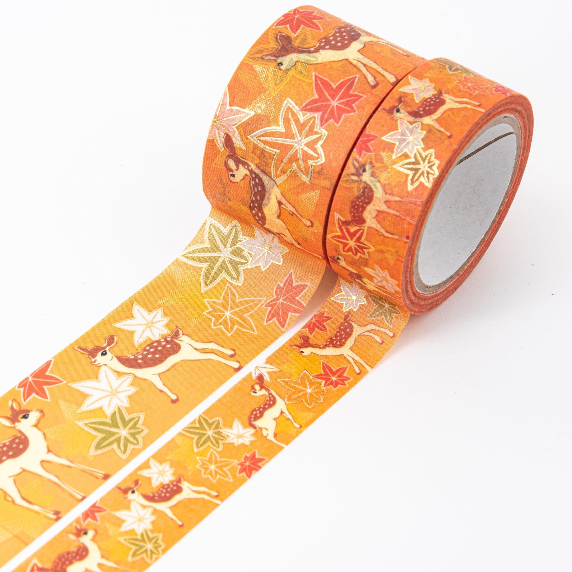 Close-up of Japanese stationery washi tape highlighting detailed deer motifs with colorful autumn leaves on a rich orange and gold background.