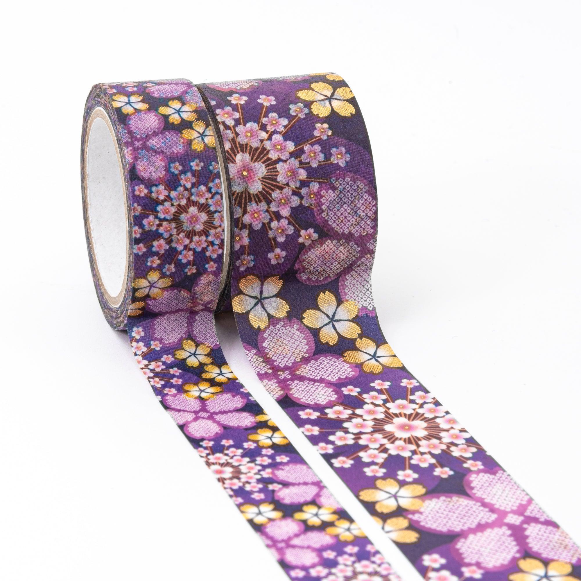 Two rolls of Japanese stationery washi tape featuring delicate sakura patterns in pink, gold, and yellow on a deep purple background.
