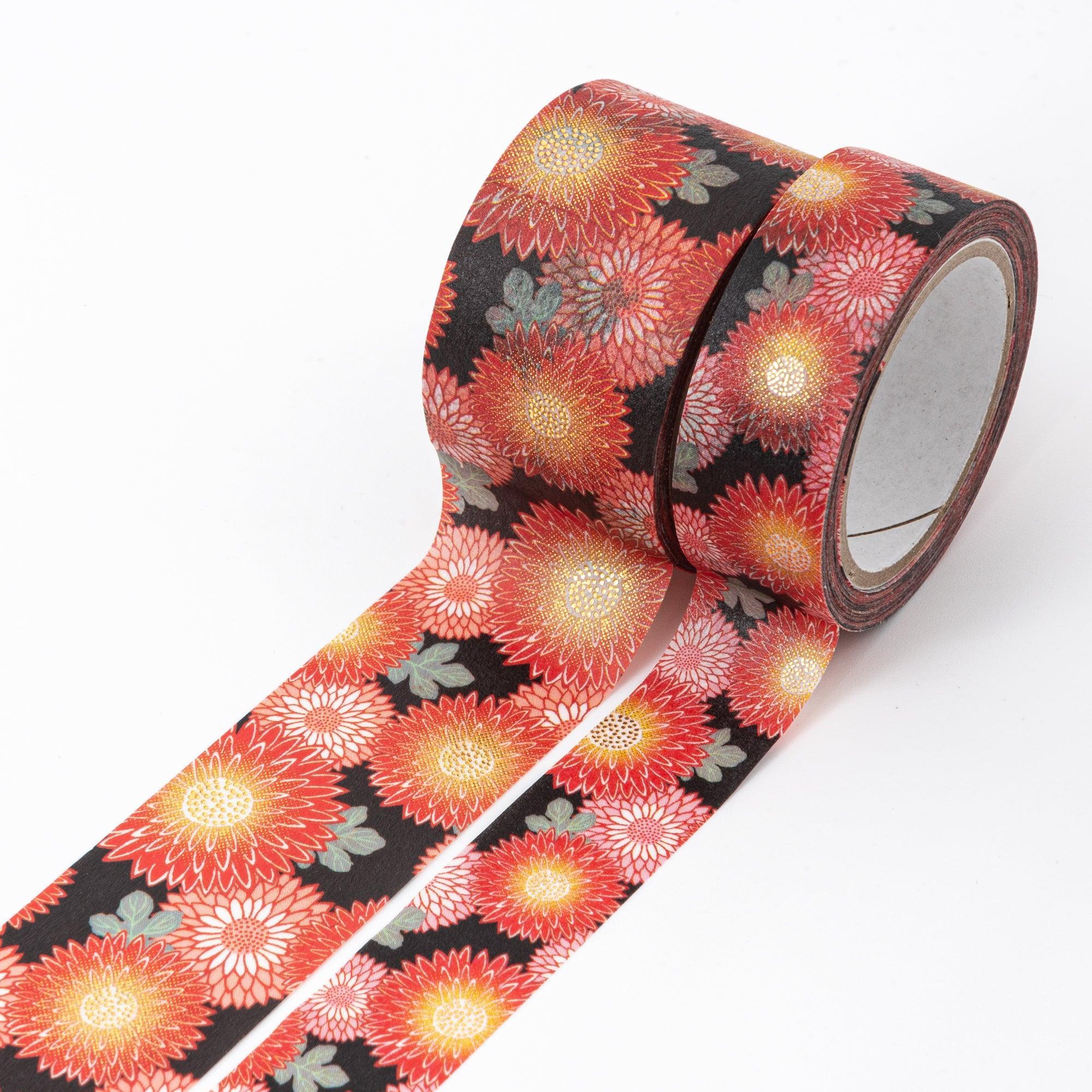 Close-up of Japanese stationery washi tape highlighting detailed chrysanthemum motifs in rich red, gold, and orange hues on a striking black background.