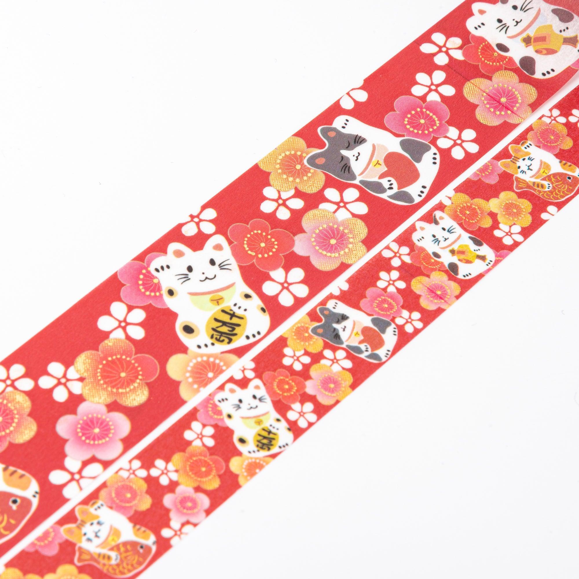 Unrolled Japanese stationery washi tape showcasing charming maneki-neko cats and plum blossoms in vibrant pink, white, and gold accents on a red base.