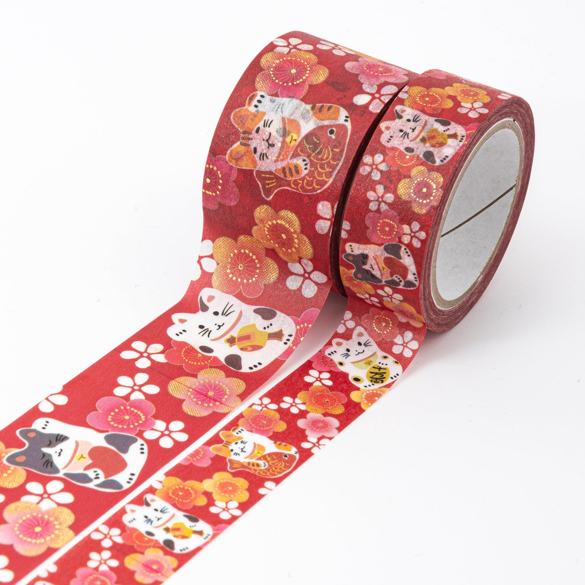 Close-up of Japanese stationery washi tape highlighting detailed lucky cats and plum blossoms with gold embellishments on a vibrant red background.