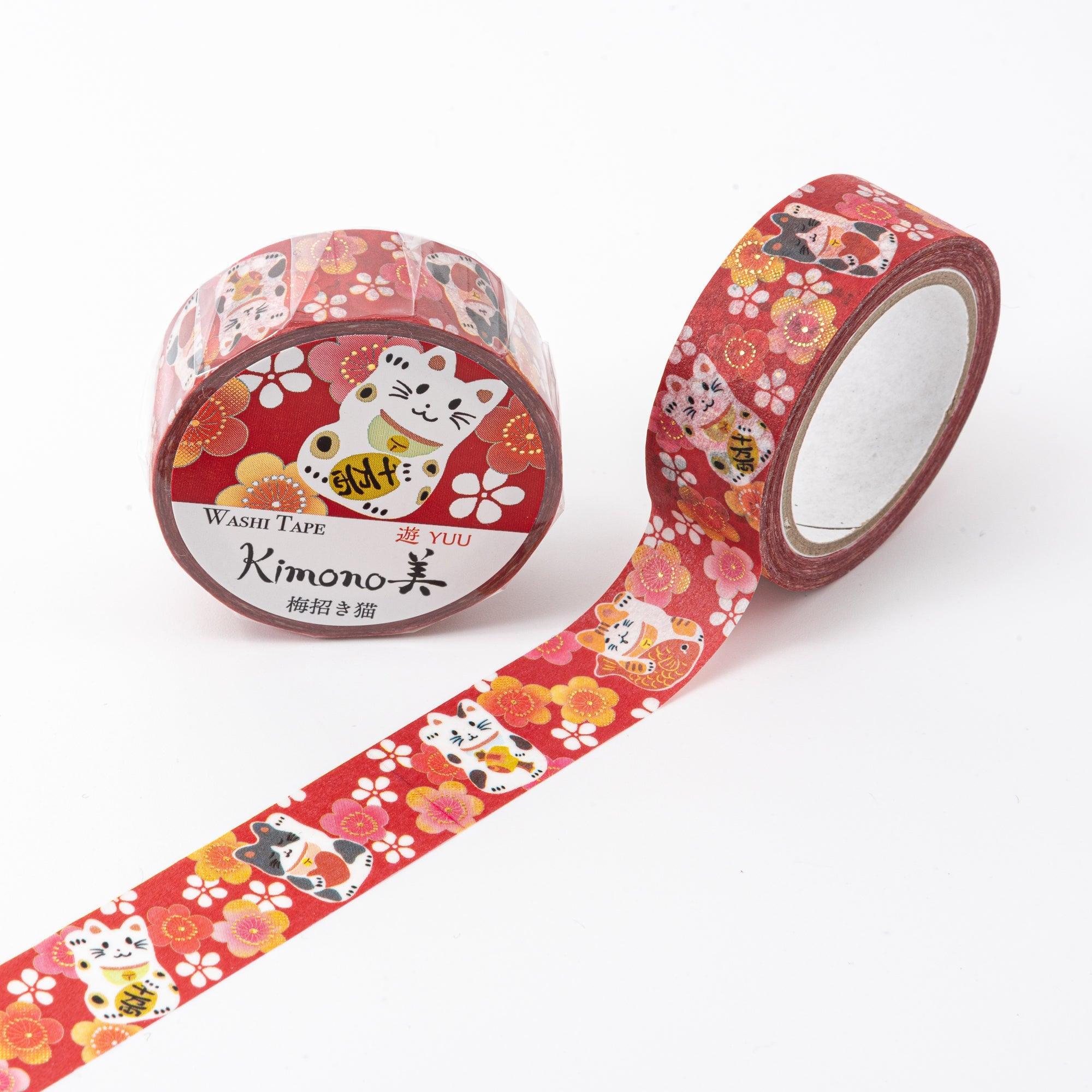 A roll of washi tape with lucky cats and floral motifs on a red base, combining pink, white, and gold accents, accompanied by its packaging.