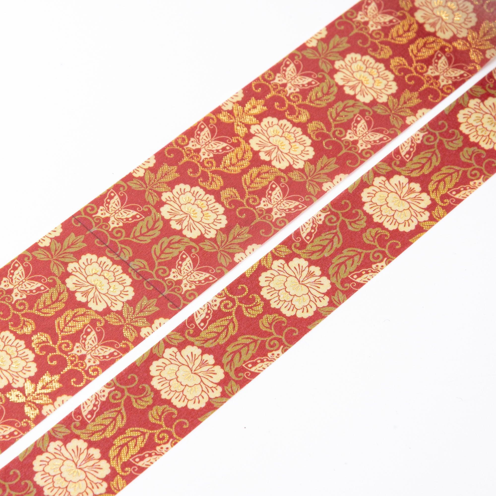 Close-up of unrolled washi tape showcasing intricate gold flowers and butterflies on a rich red background.