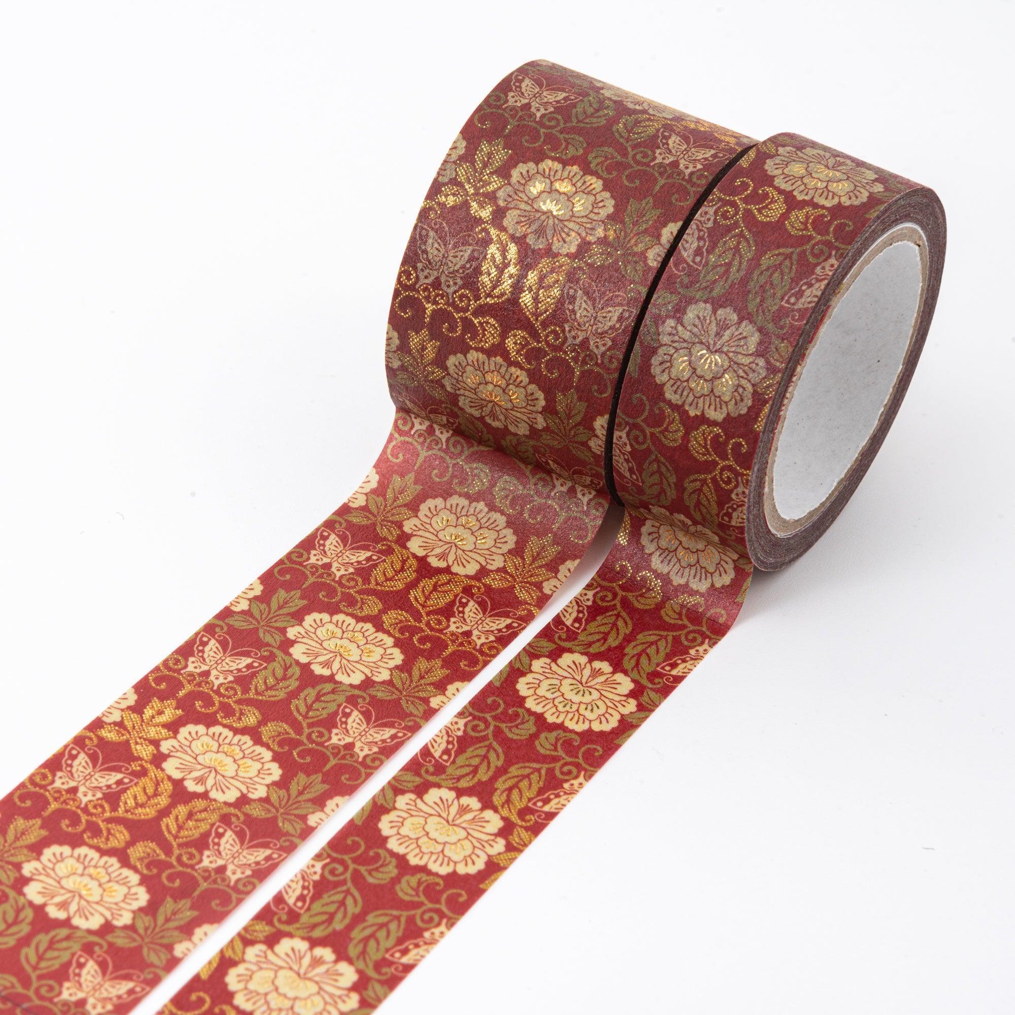 Two red washi tape rolls adorned with gold floral and butterfly designs, unrolled to display the vibrant, ornate patterns.