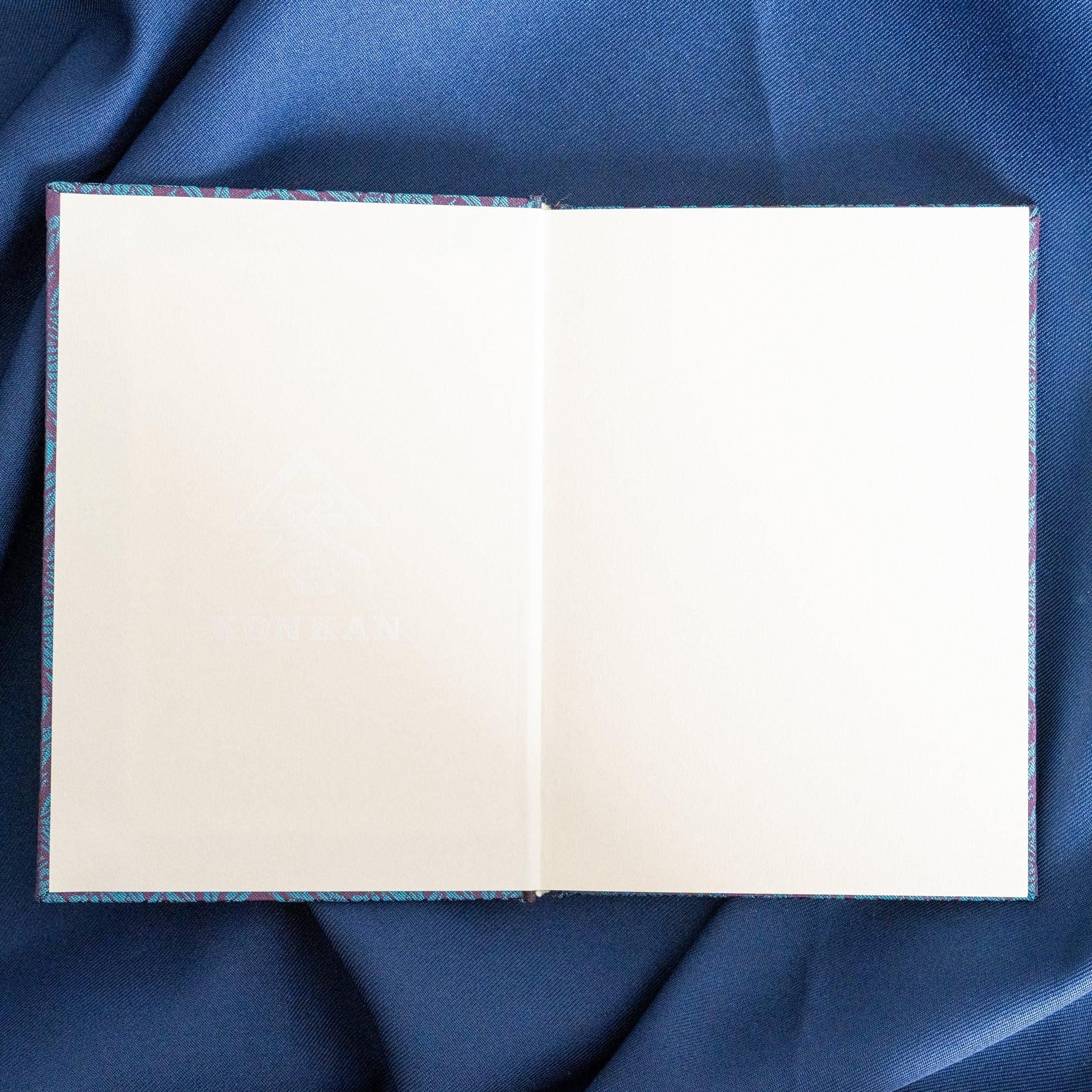 Kiri Take Ho-o Nishijin silk Homeicho notebook open spread with two blank white pages and teal cover at binding