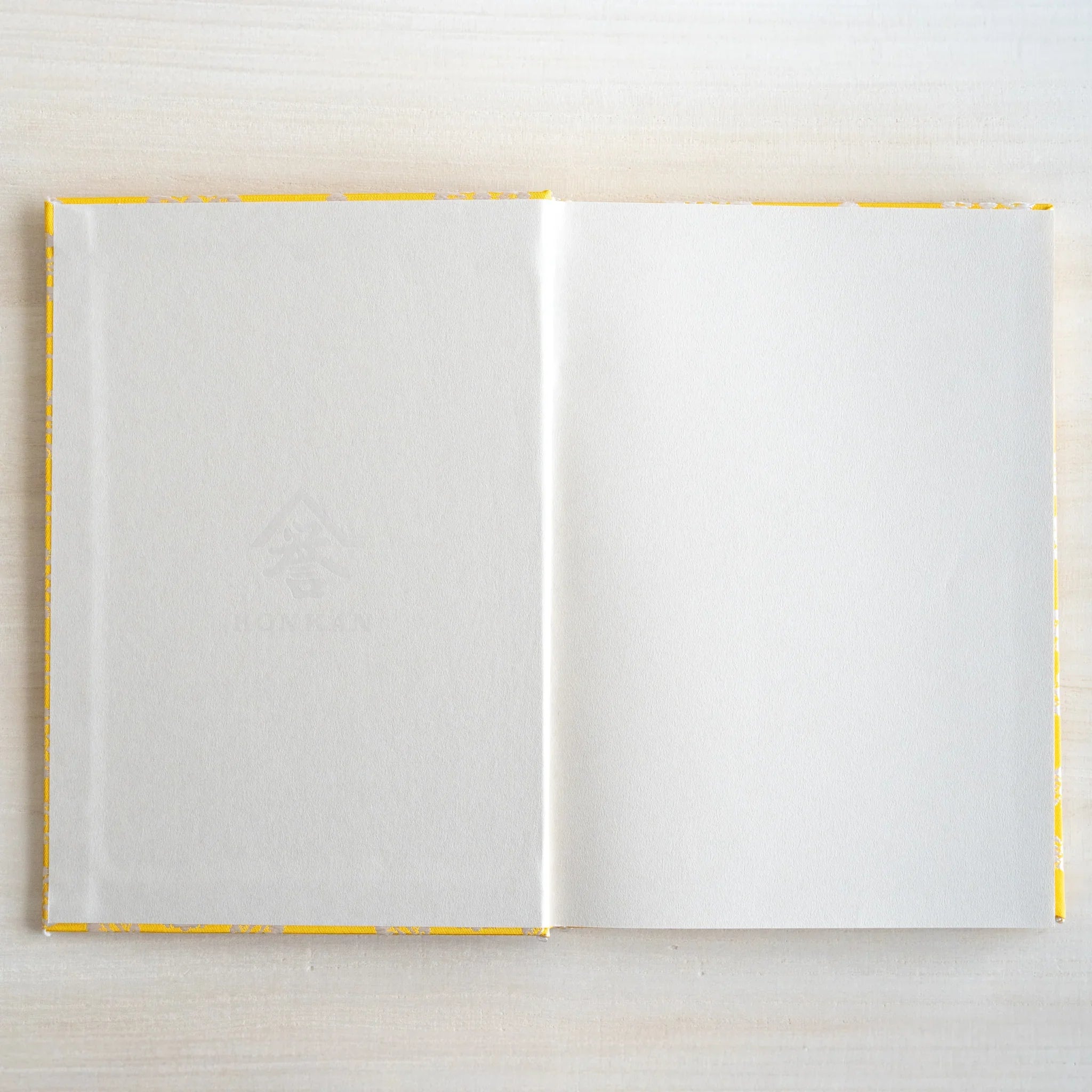 Ko Aoi Nishijin silk Homeicho notebook opened flat overhead showing blank white pages bordered by golden Ko Aoi cover