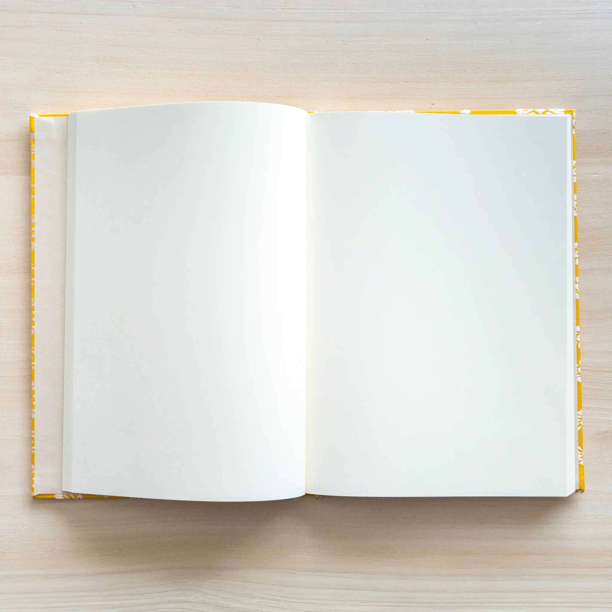 Ko Aoi Nishijin silk Homeicho notebook opened showing blank white page spread with golden Ko Aoi cover border on wood