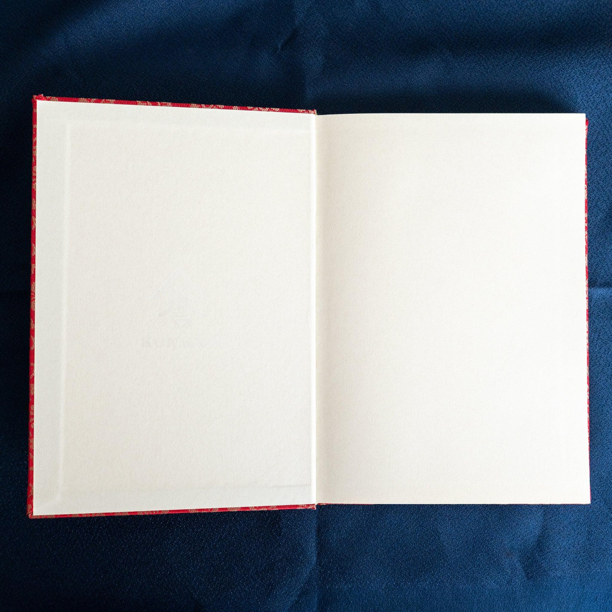 Ko Aoi Nishijin silk Homeicho notebook opened flat showing blank cream pages with vermilion cover edges on blue fabric
