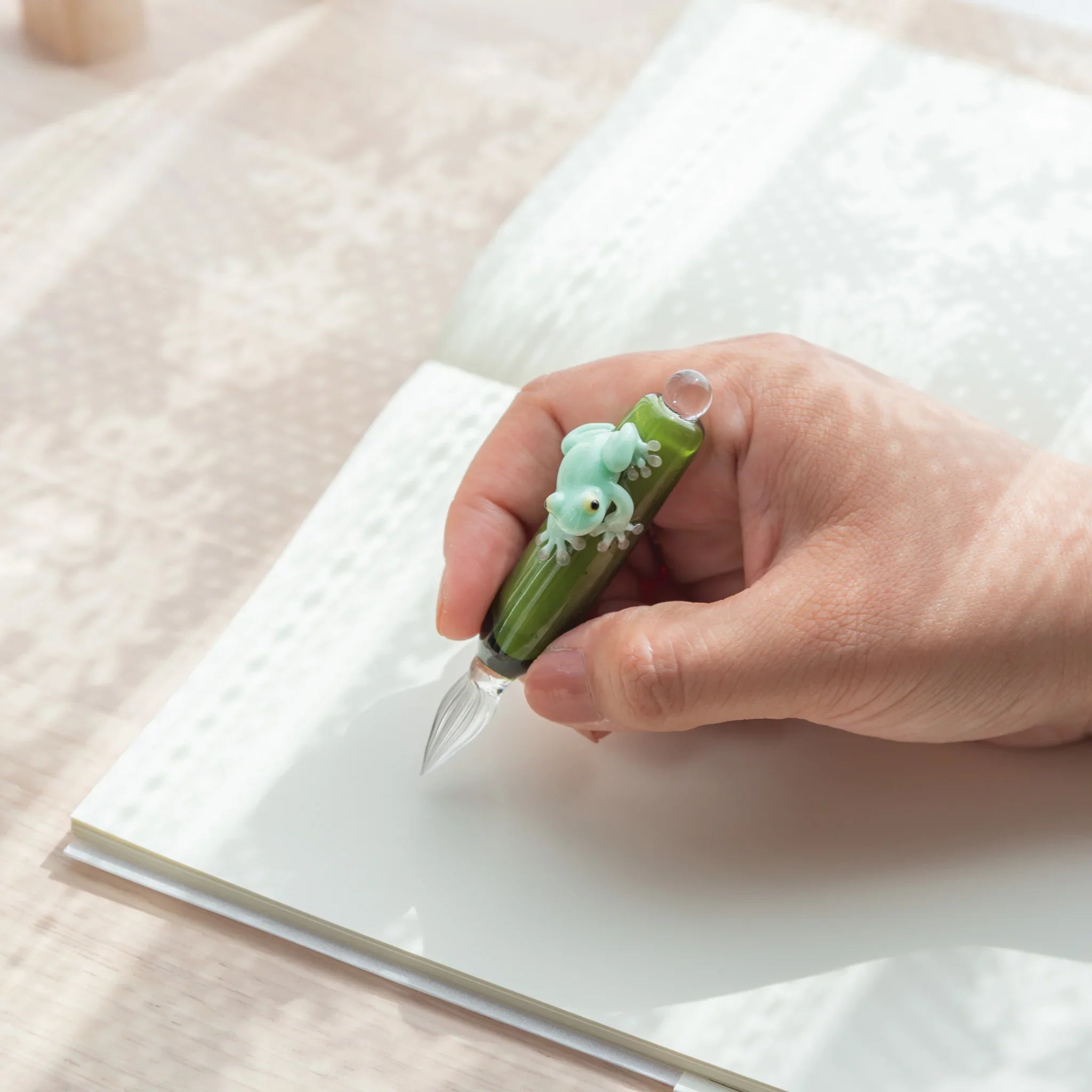Japanese frog glass dip pen featuring mint green resin creature holding hand-blown glass ink container well