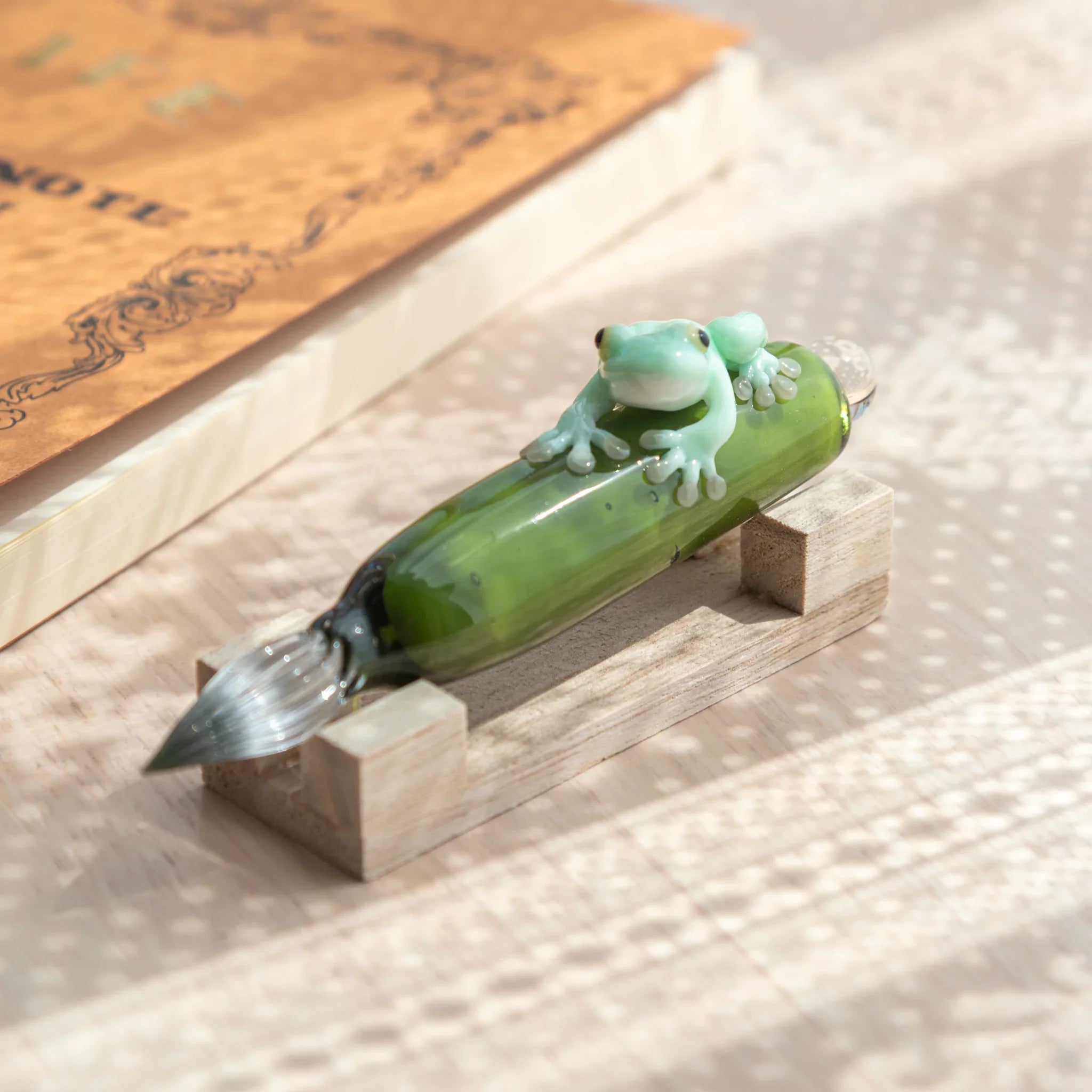 Glass dip pen frog design featuring detailed ceramic amphibian sculpture on vibrant colored glass base