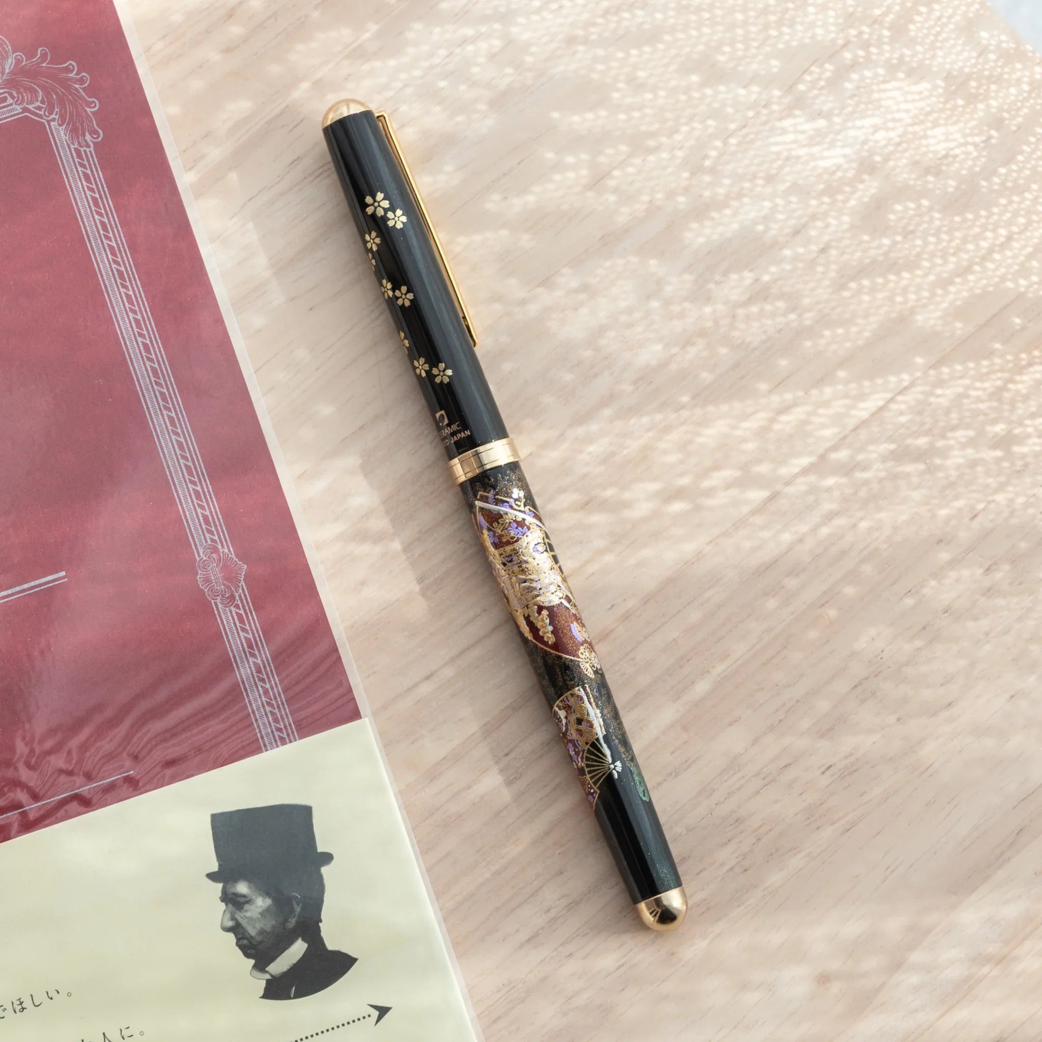 Black Yamanaka lacquer Japanese ballpoint pen with gold sakura on cap and Kyoto maiko and fan maki-e motifs on barrel