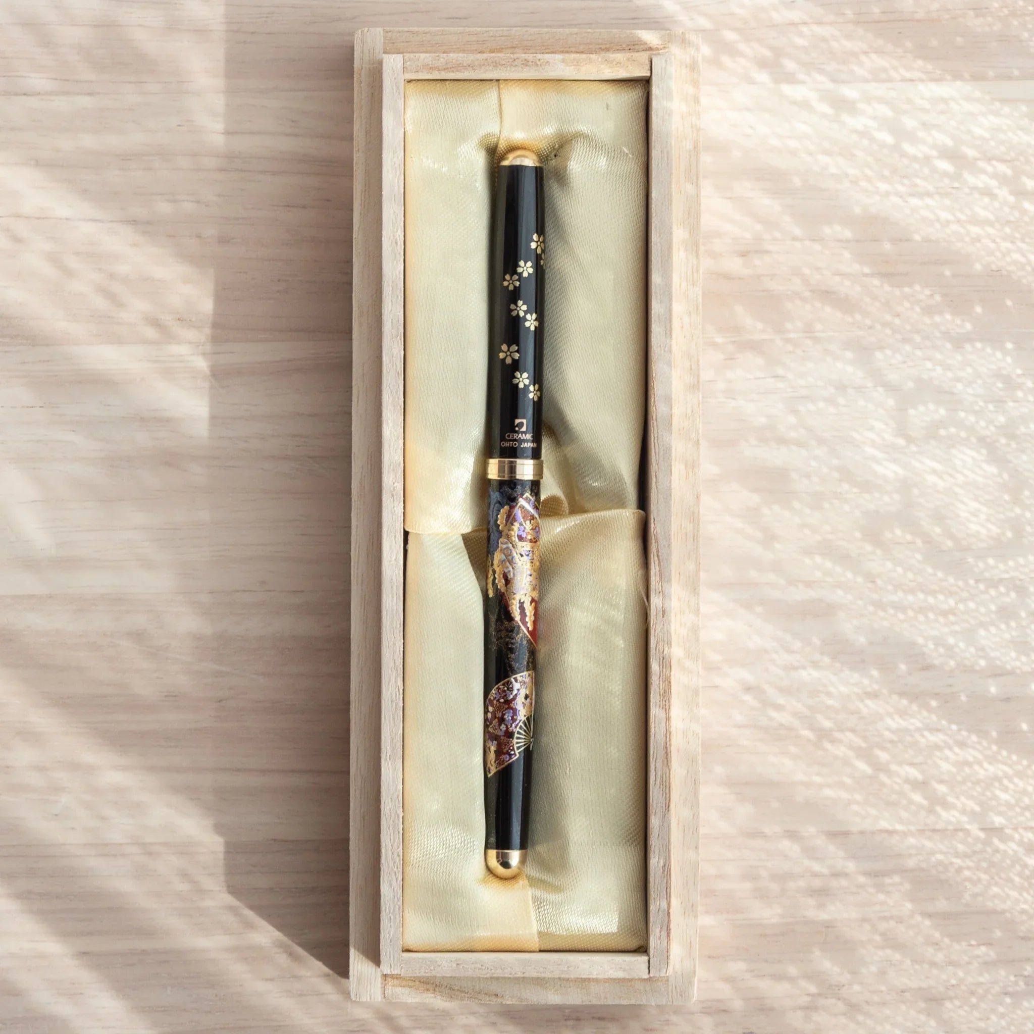 Japanese Ballpoint Pen with cherry blossom and fan design in gold Lacquer, resting in a silk-lined gift box.