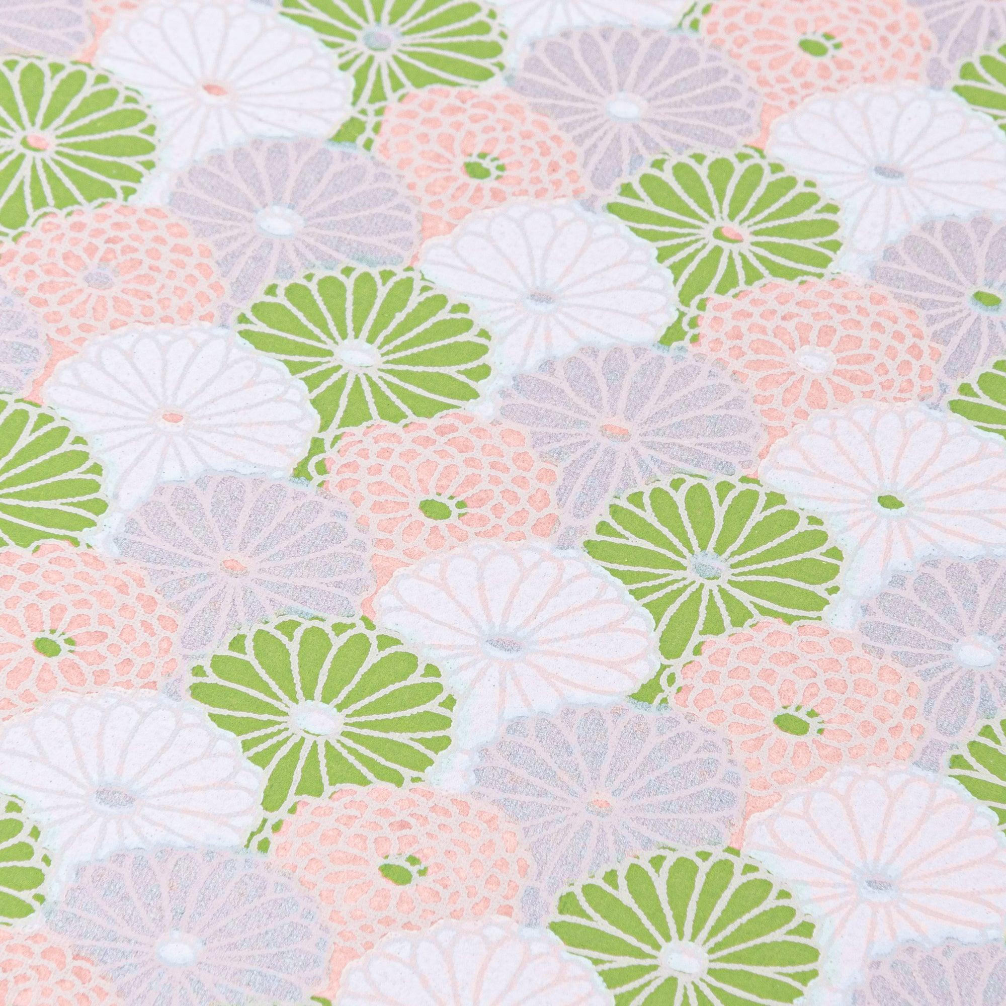 A Japanese notebook with a Yuzen washi cover, showcasing a pastel fan pattern in green, pink, and lilac, with a silver spiral binding and elastic band.
