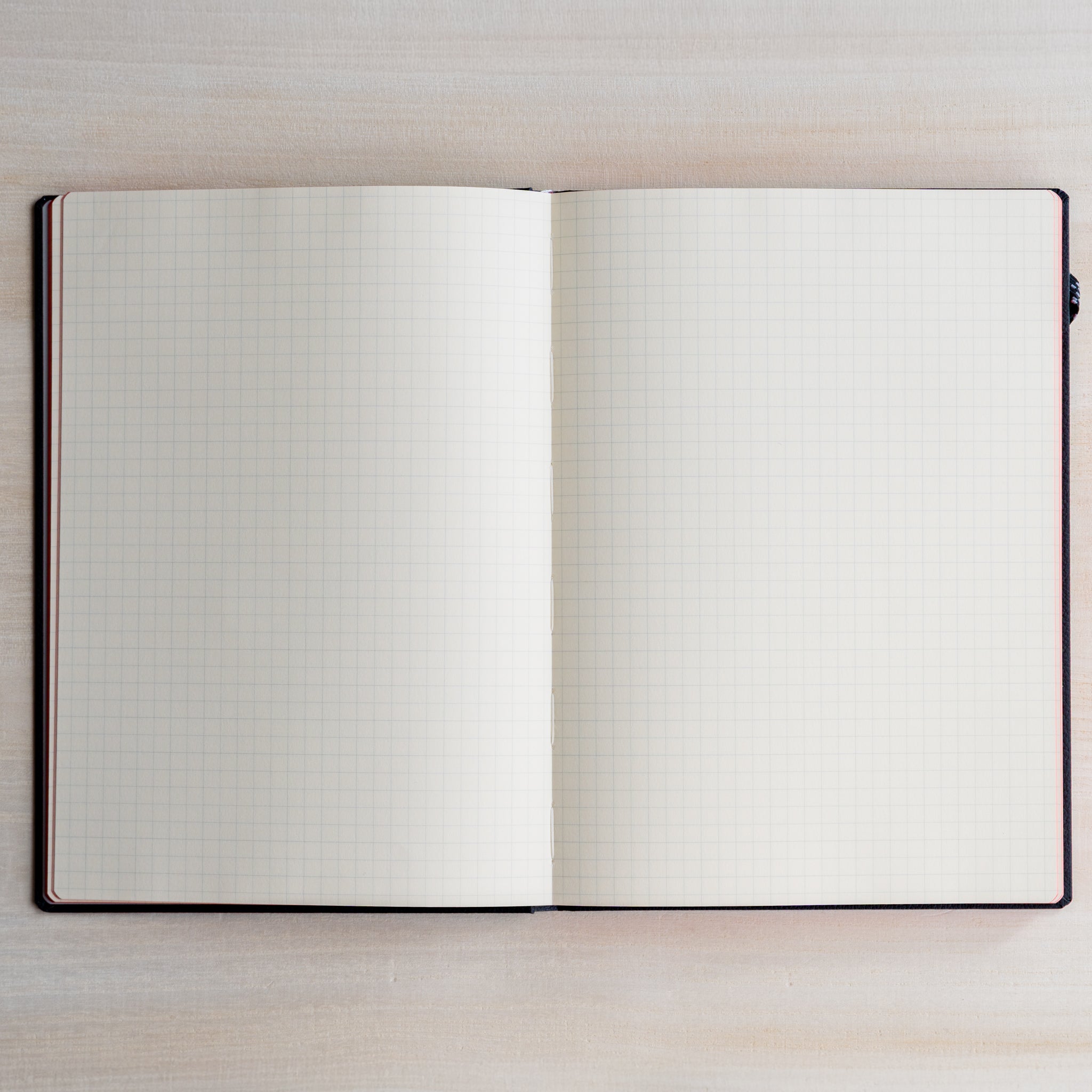 Life noble hard cover notebook A5 open flat showing cream grid L Writing Paper on both pages, clean layout on light desk