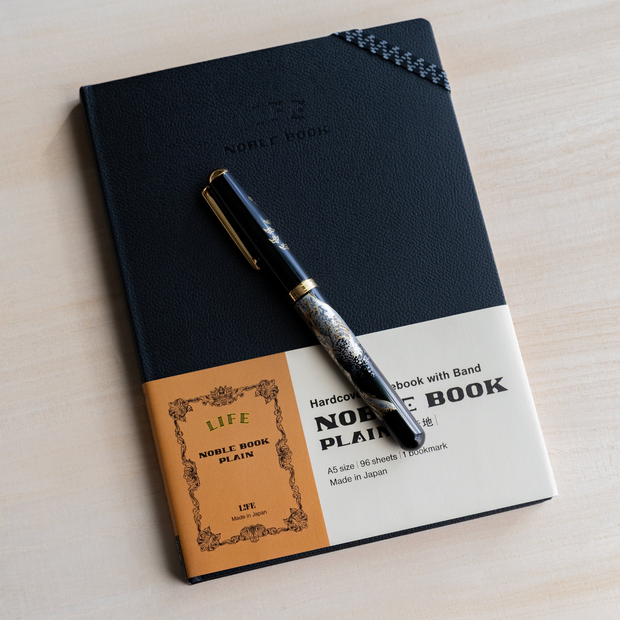 Life Noble notebook A5 hard cover with fountain pen resting on cover, showcasing Japanese design for writers