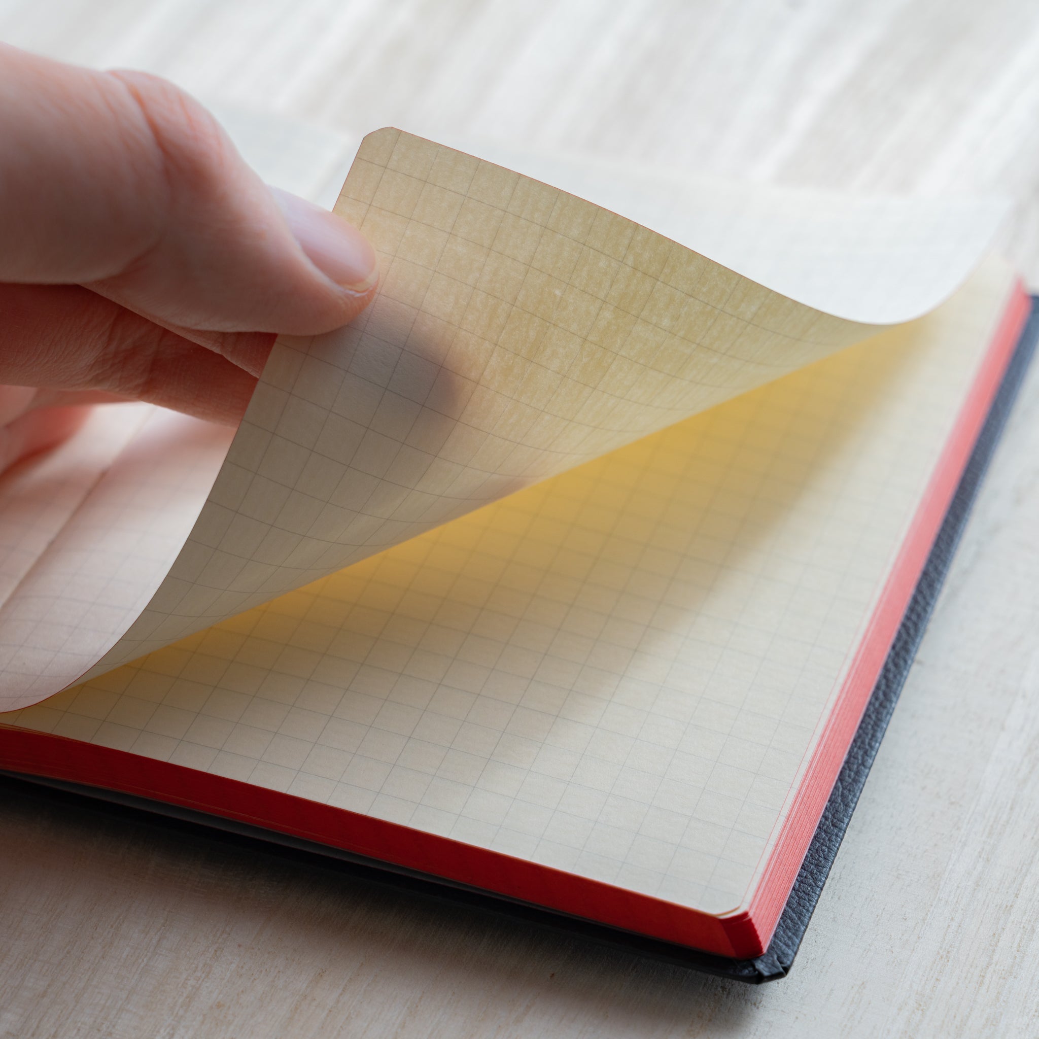 Life Noble notebook A6 close-up of hand turning grid L Writing Paper, showing smooth cream pages and fountain pen friendly quality