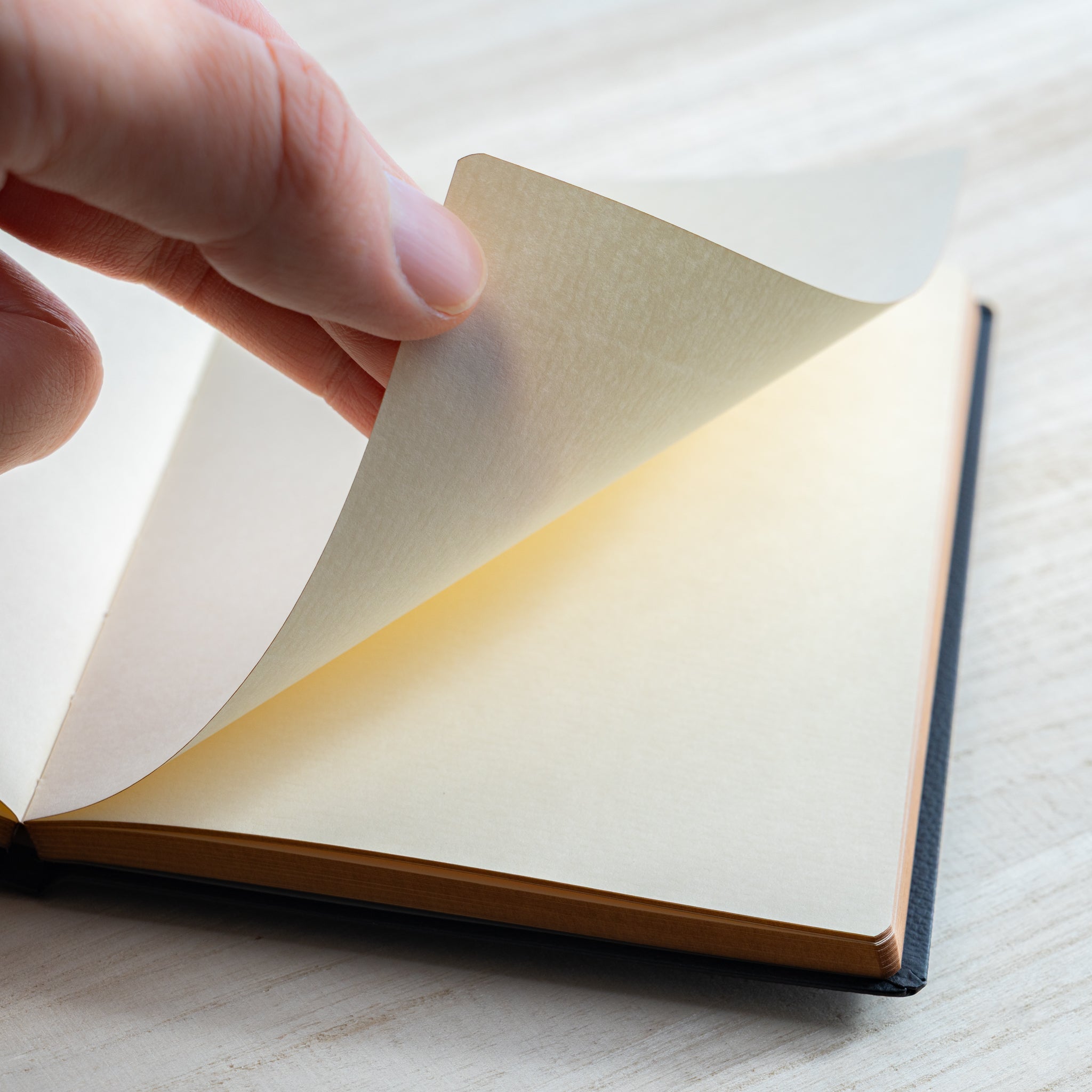 Life Noble notebook A6 close-up of hand turning cream L Writing Paper, showing smooth texture and fountain pen friendly quality