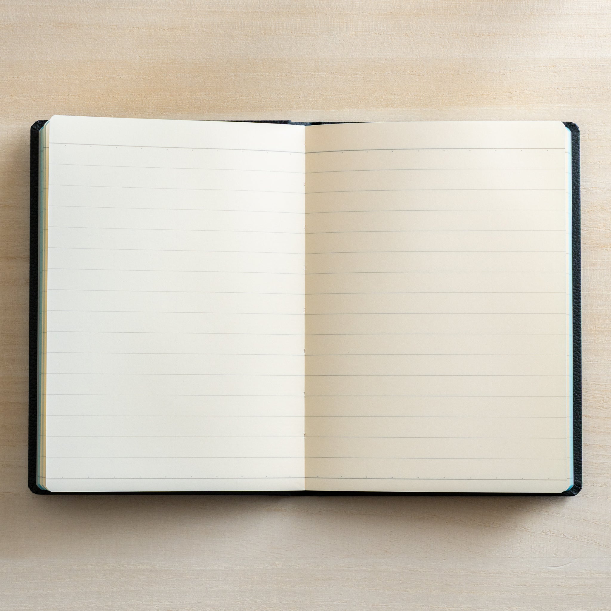 Life Noble notebook A6 open flat with lined L Writing Paper on desk, showing clean ruling, cream pages, and compact layout