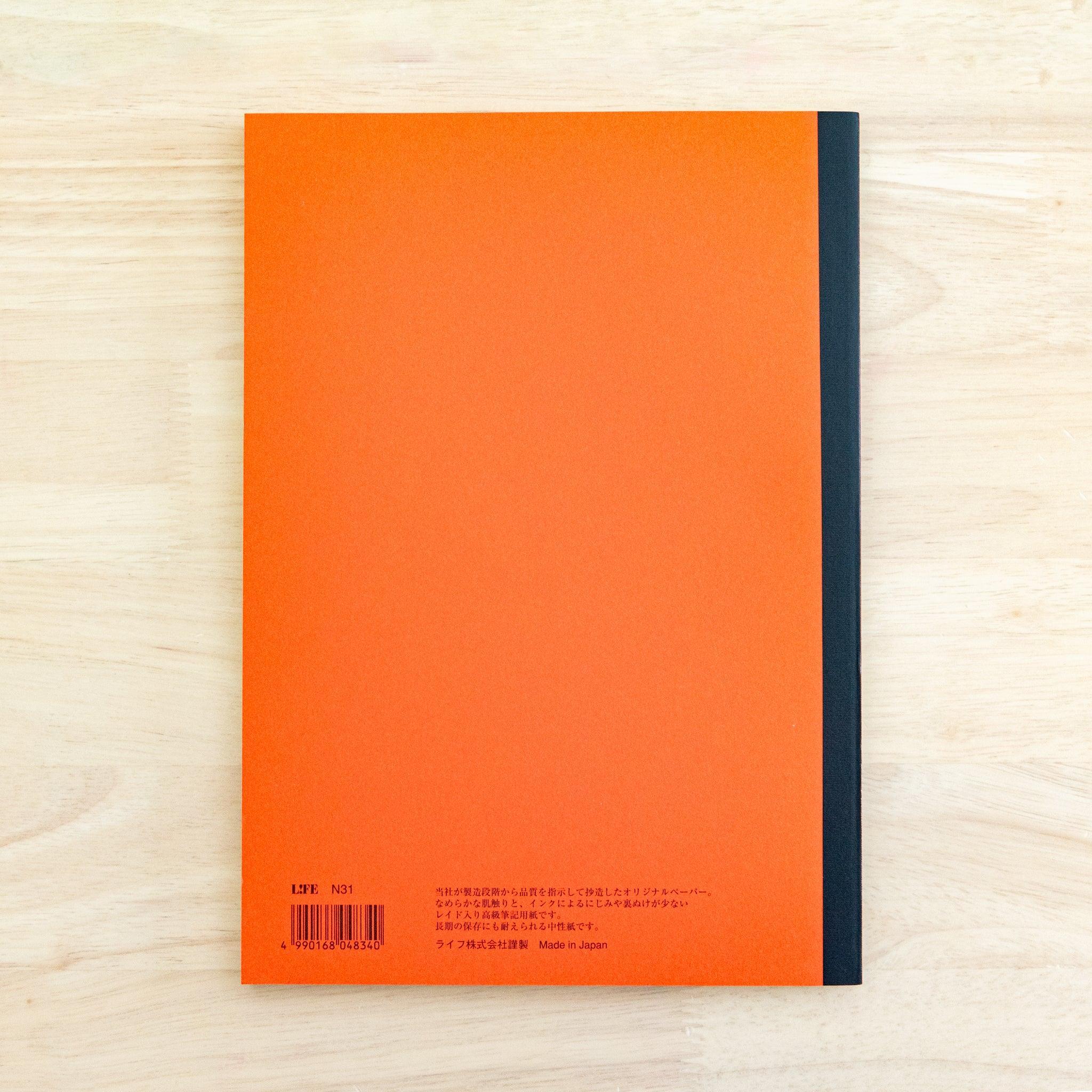 A single "LIFE Noble Note Section" notebook with an orange cover, black spine, ornate border design, and 100 sheets, displayed on a wooden surface.