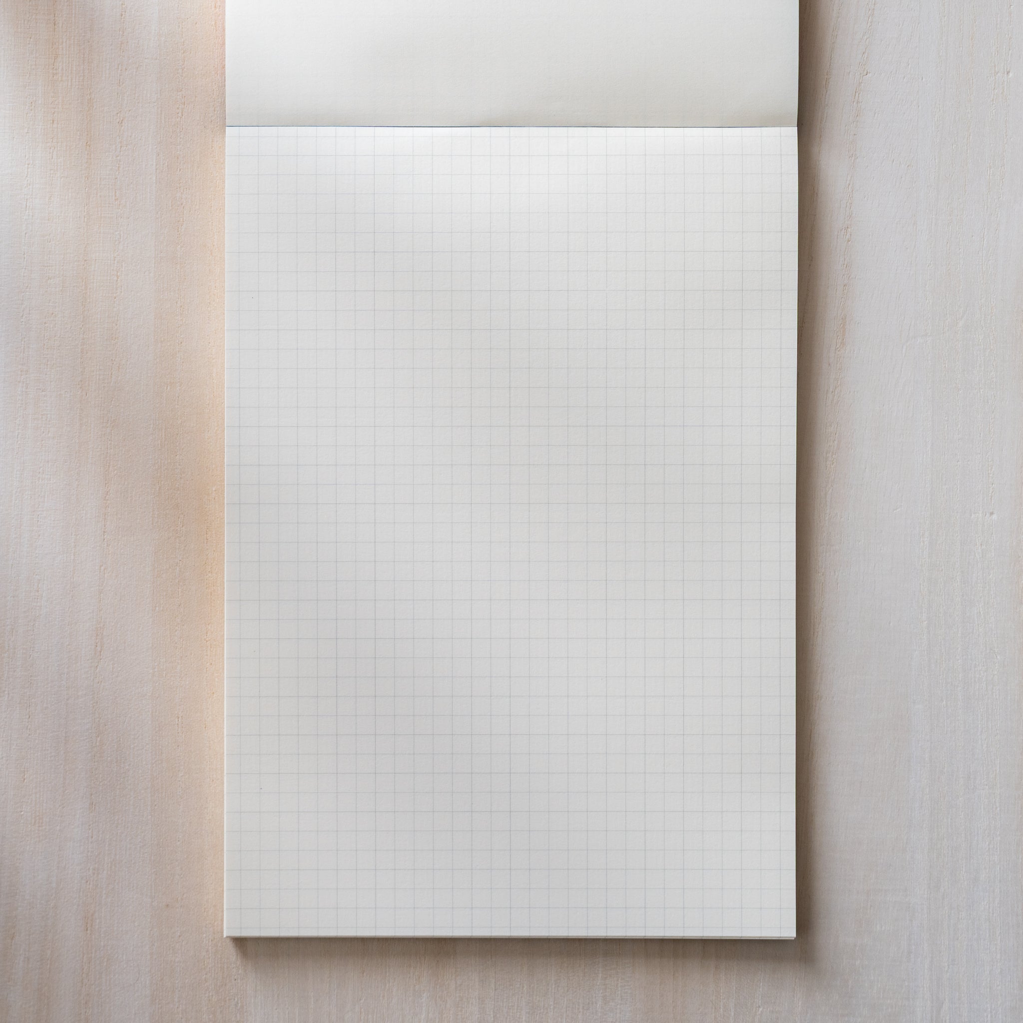 Life Noble writing pad grid page shown flat with even squares and top margin, smooth cream Japanese paper for precise notes