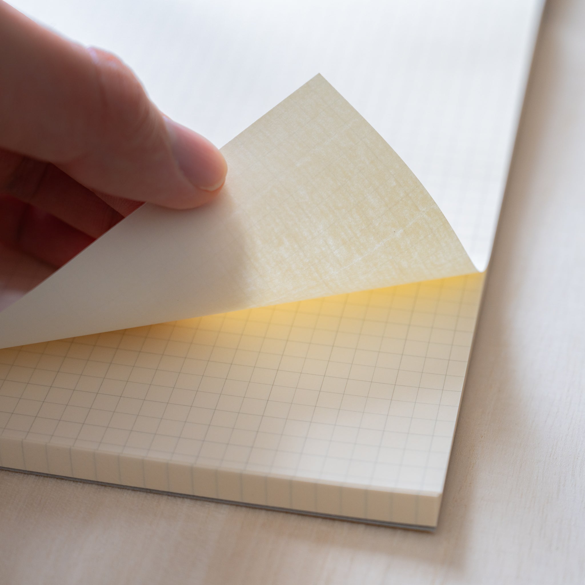 Life Noble writing pad page being lifted to show grid pattern and smooth cream paper, Japanese stationery pad for fountain pens