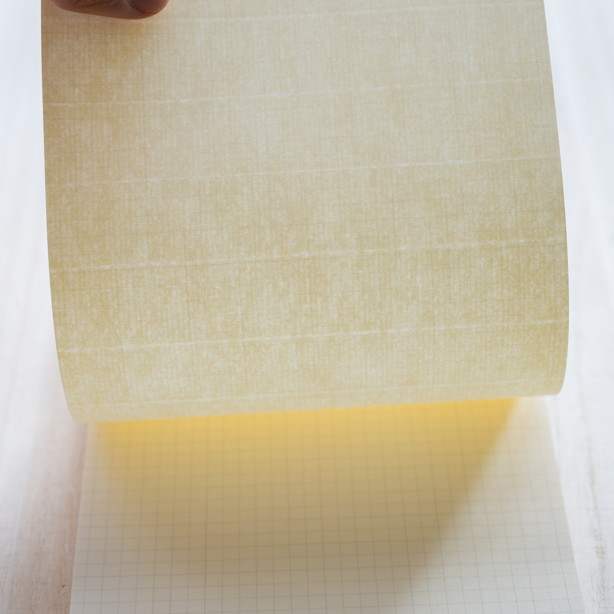Life Noble writing pad showing blank cream sheet lifted over grid pages, smooth Japanese paper texture for fountain pen writing