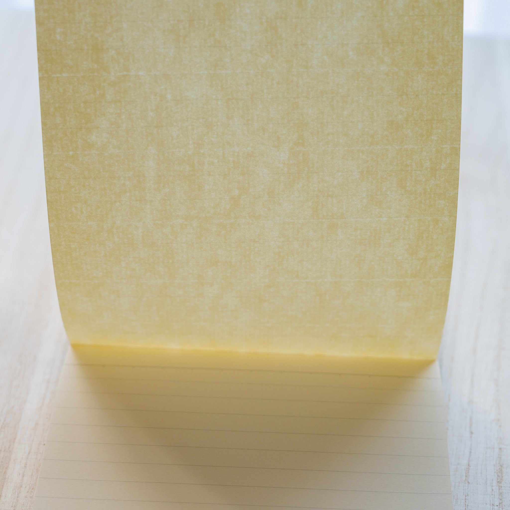 Life noble writing pad B6 close-up of blank cream L Writing Paper lifted upright, ruled page visible beneath, smooth texture