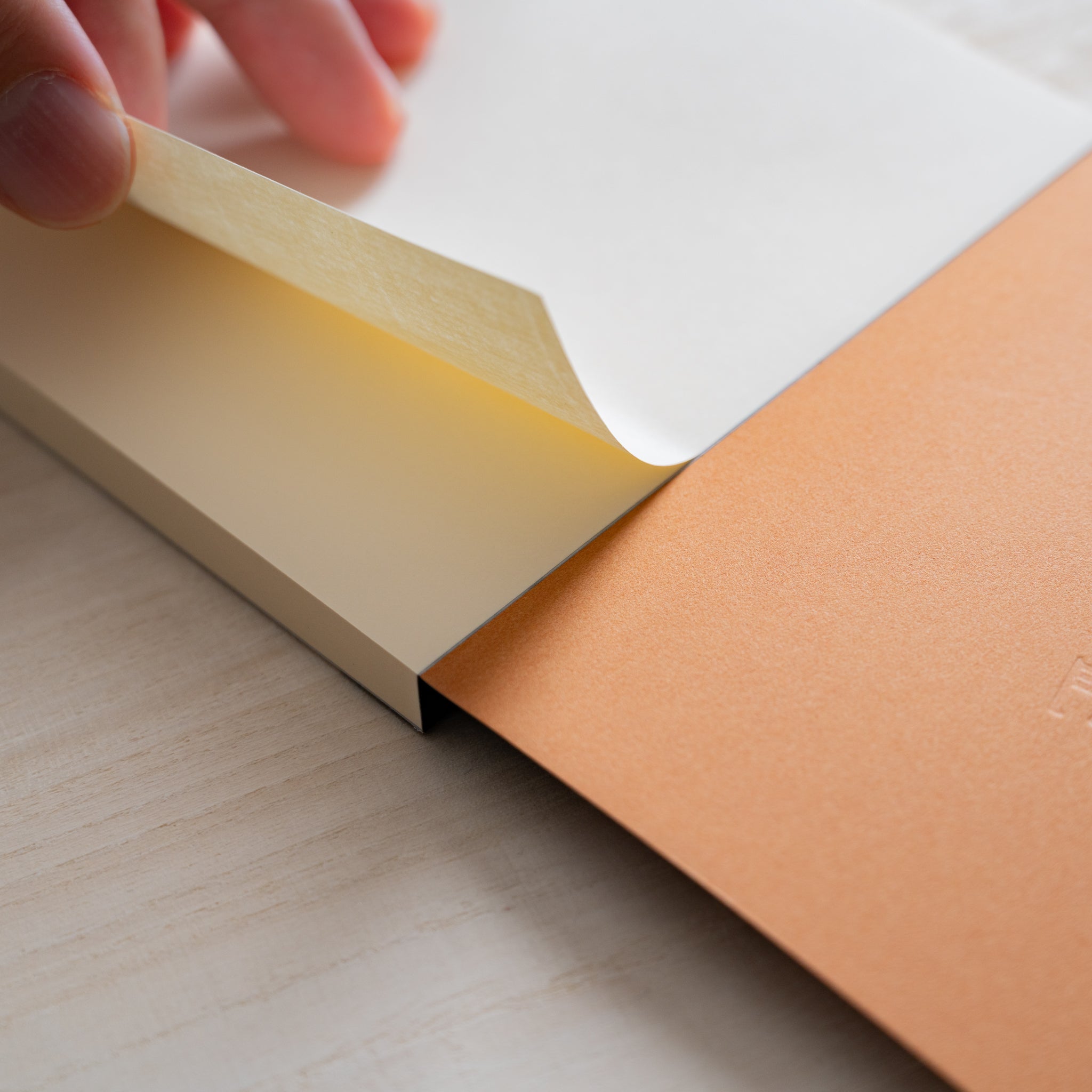 Life noble writing pad B6 close-up of lifted corner showing cream L Writing Paper thickness and brown backing board