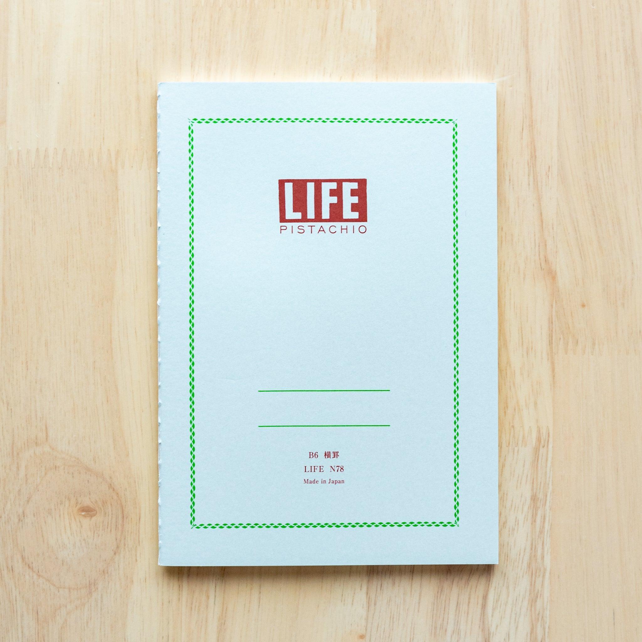 A single "LIFE Pistachio" notebook in B6 size with a light gray cover, red logo, and minimal border design, displayed on a wooden surface.