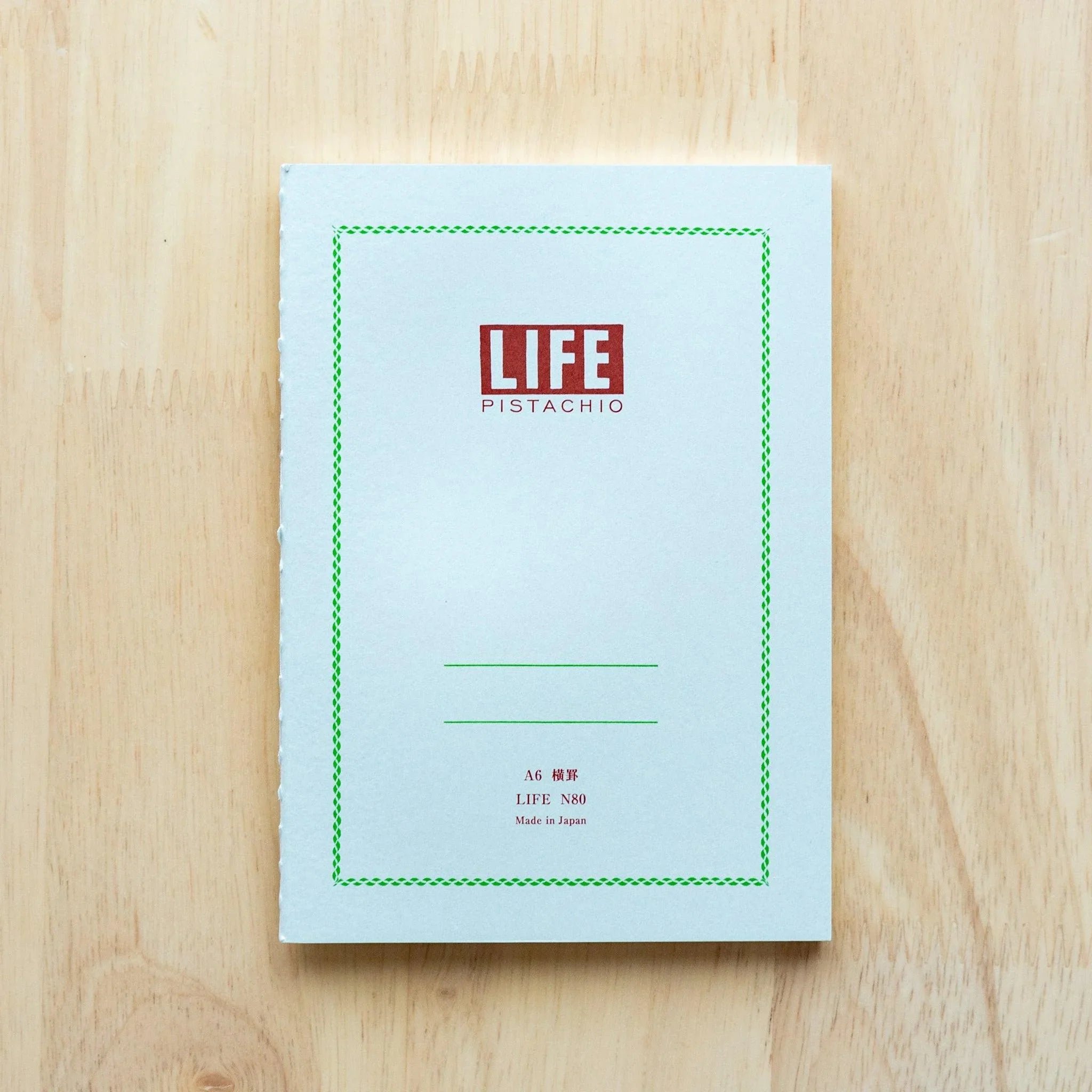 Pistachio-colored LIFE A5 journal with branding, detail shot of spine branding label and binding, LIFE Japan