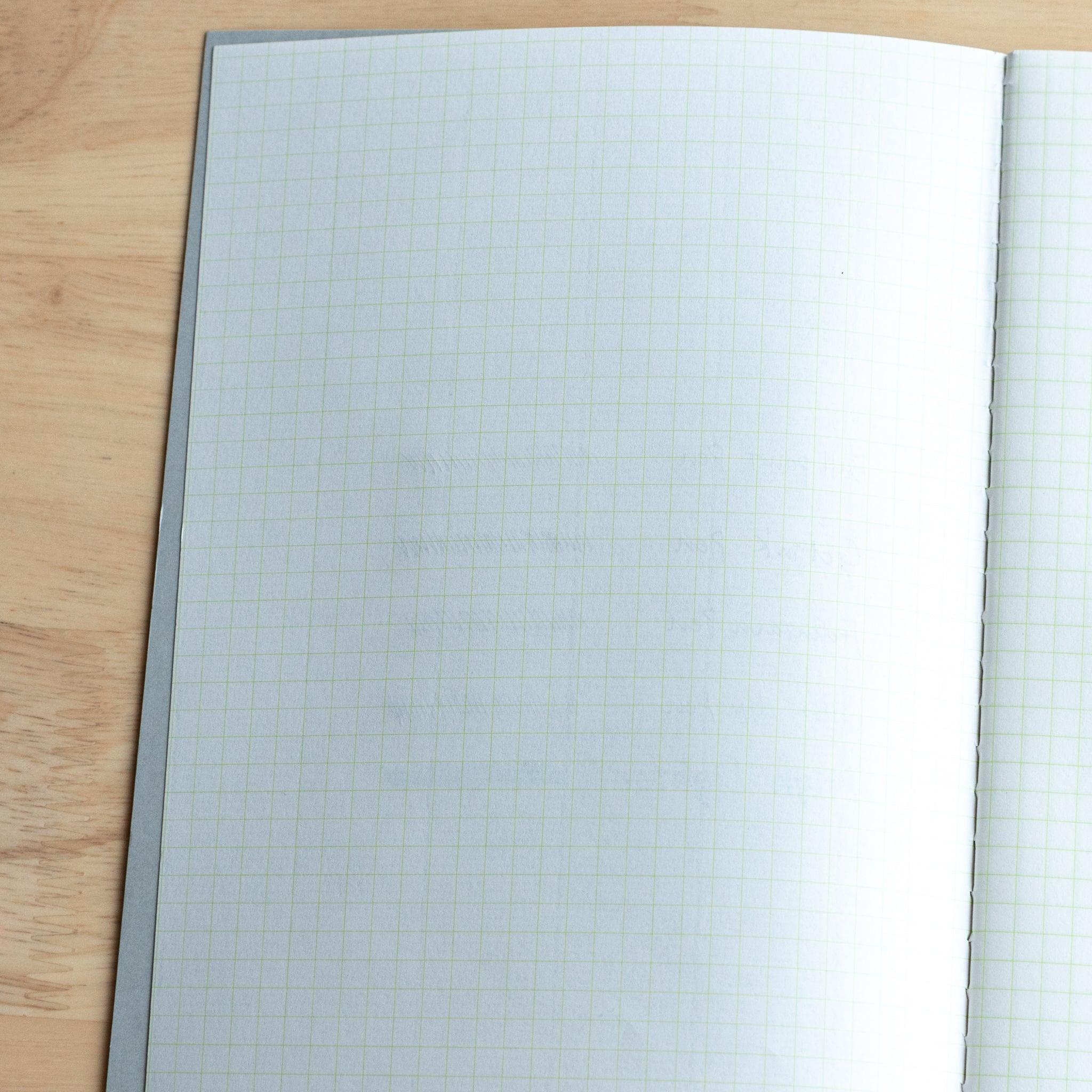 The next notebook page shows slight ink ghosting from the previous writing, with faint lines and text visible through the paper.