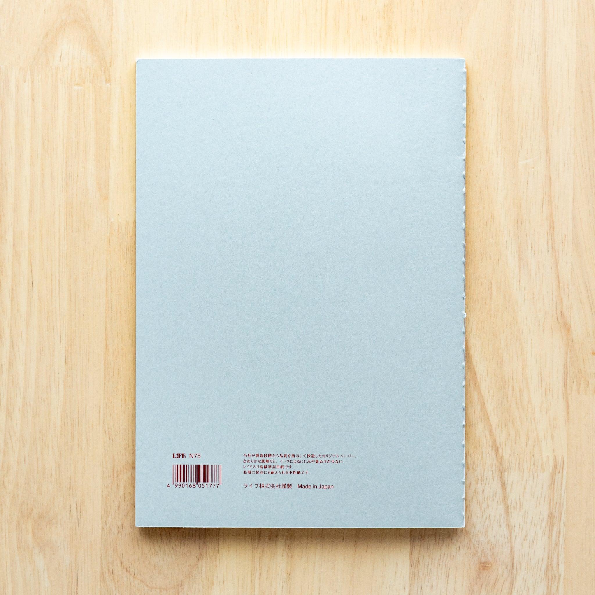 A single "LIFE Pistachio" notebook in A5 size with a light gray cover, green logo, and minimal border design, displayed on a wooden surface.
