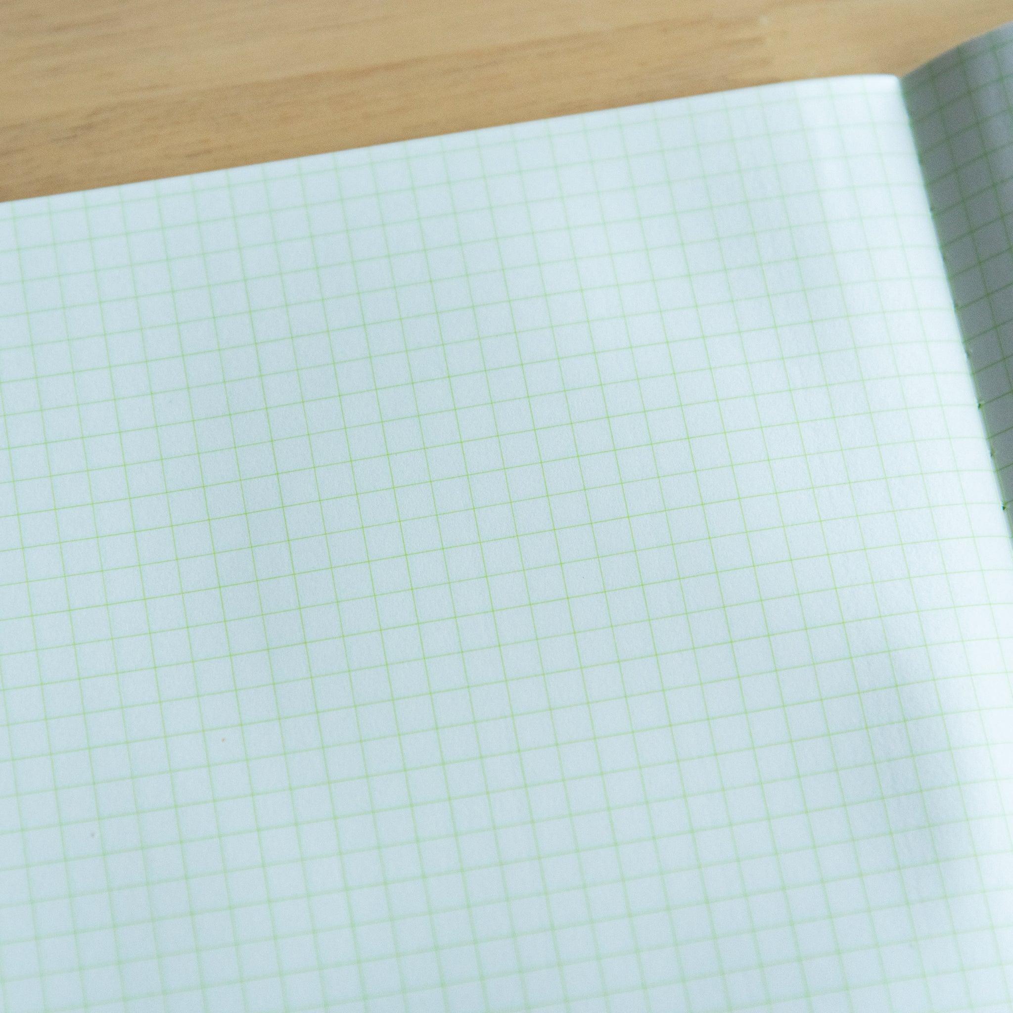 A close-up view of light green grid paper with fine squares, showing texture and details of the Japanese notebook.