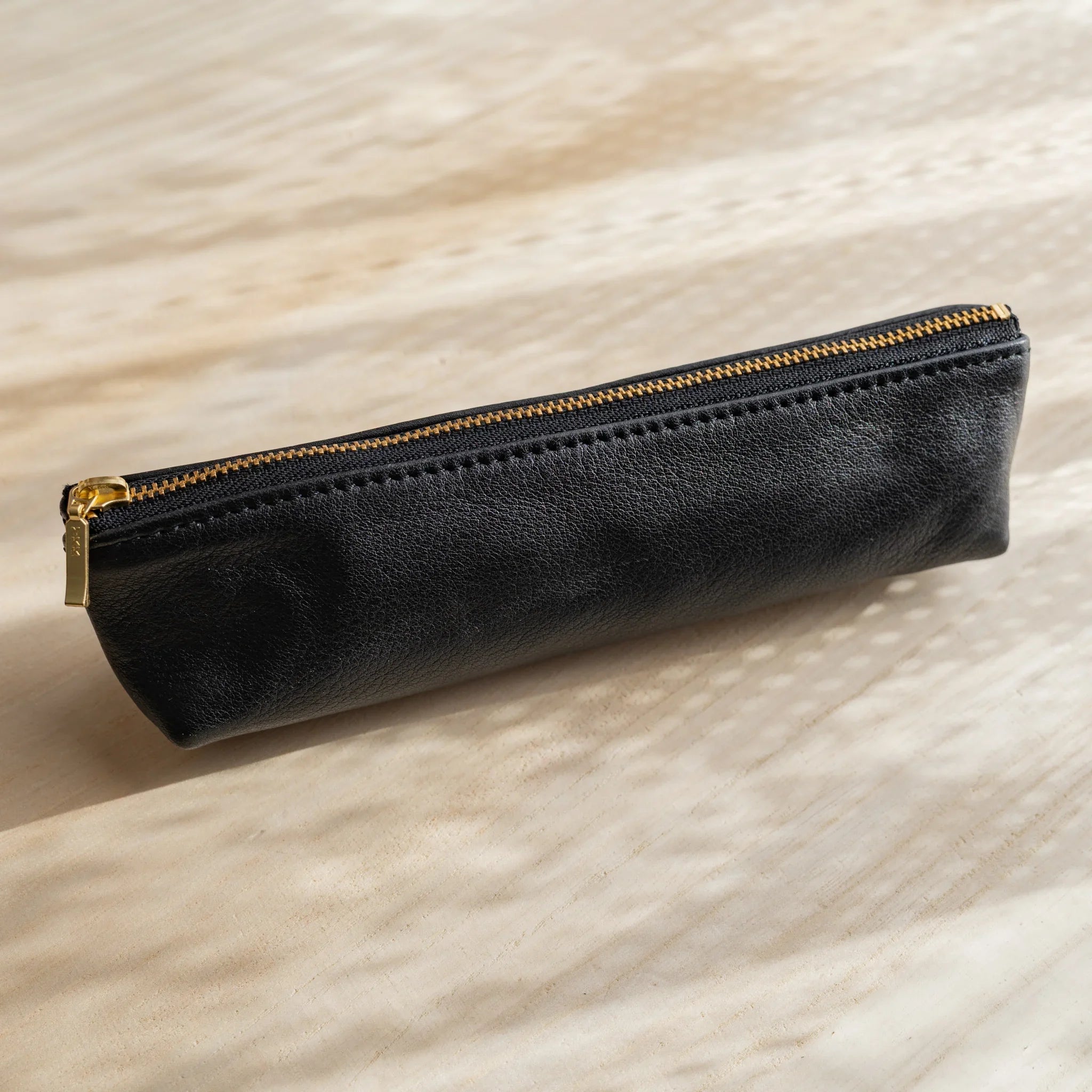 Life steerhide leather pen case in black with gold zipper and cylindrical shape and features and features