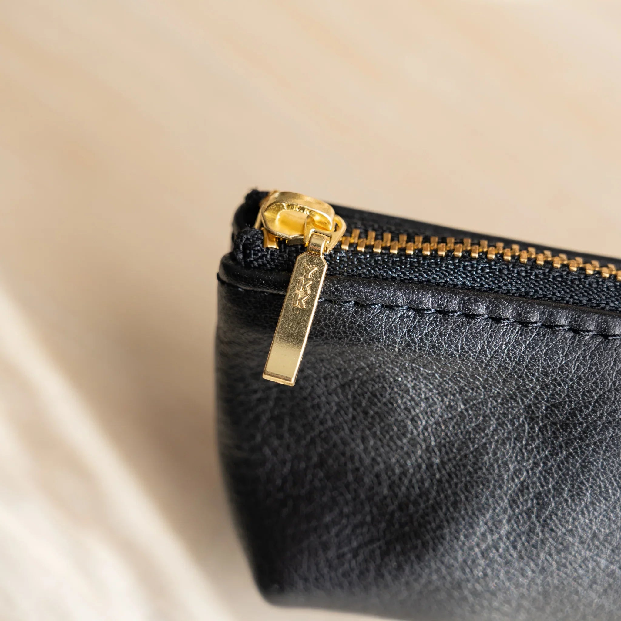 Close-up of Japanese pen case zipper pull with gold hardware and textured black leather