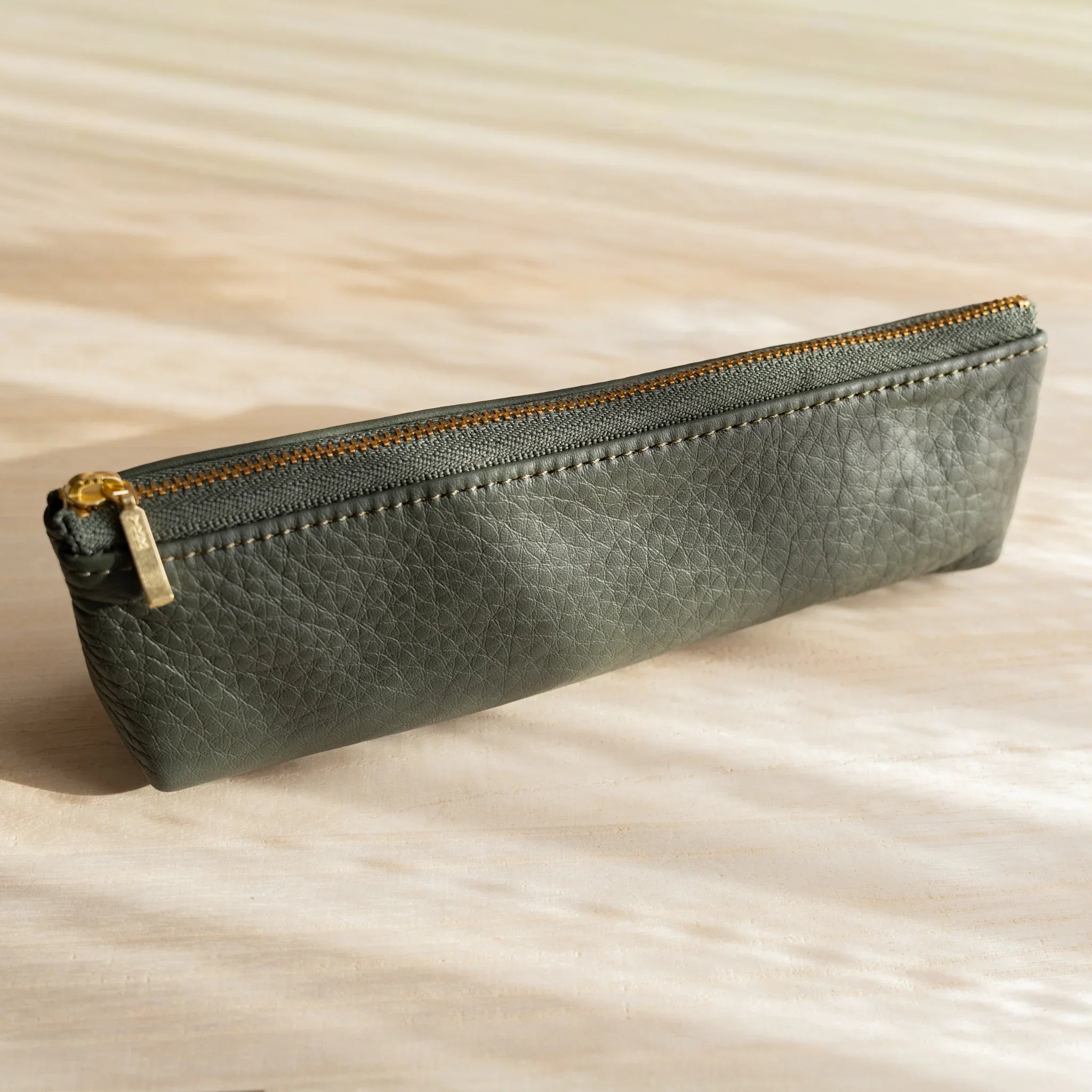Life steerhide leather pen case in green with gold zipper and cylindrical shape and features and features