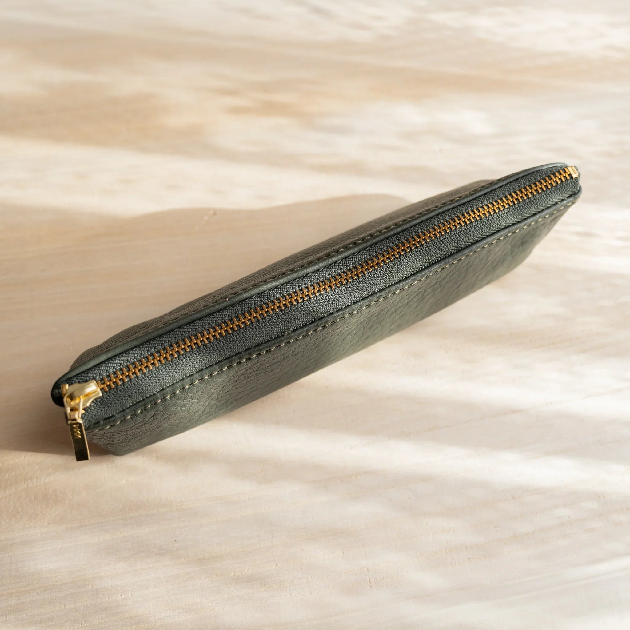 Zipper detail on green case showing gold metal hardware and features and features and features and features