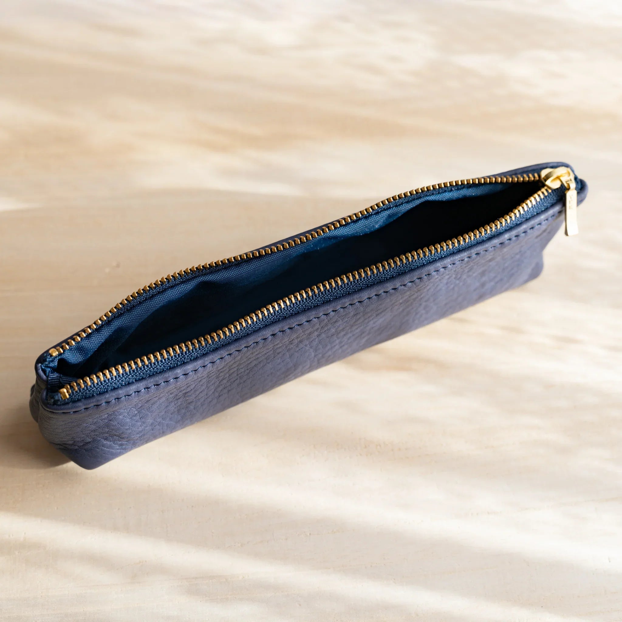 Zipper mechanism on navy case showing gold hardware detail and features and features and features and features