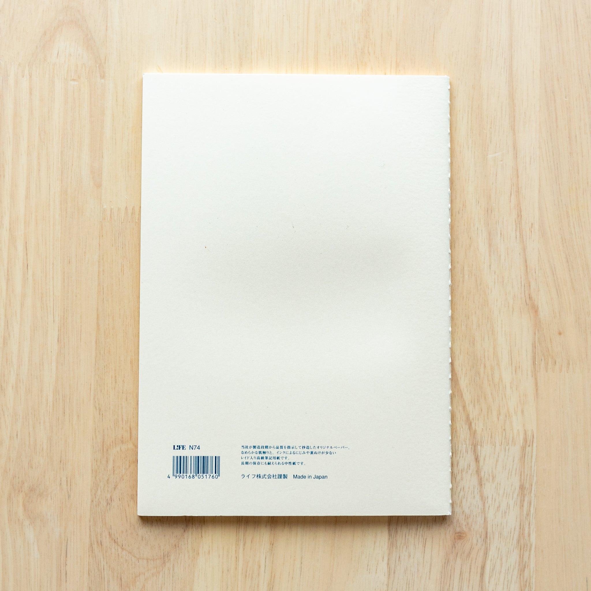 A single "LIFE Vermilion" notebook in A5 size with a white cover, blue logo, and minimal border design, displayed on a wooden surface.