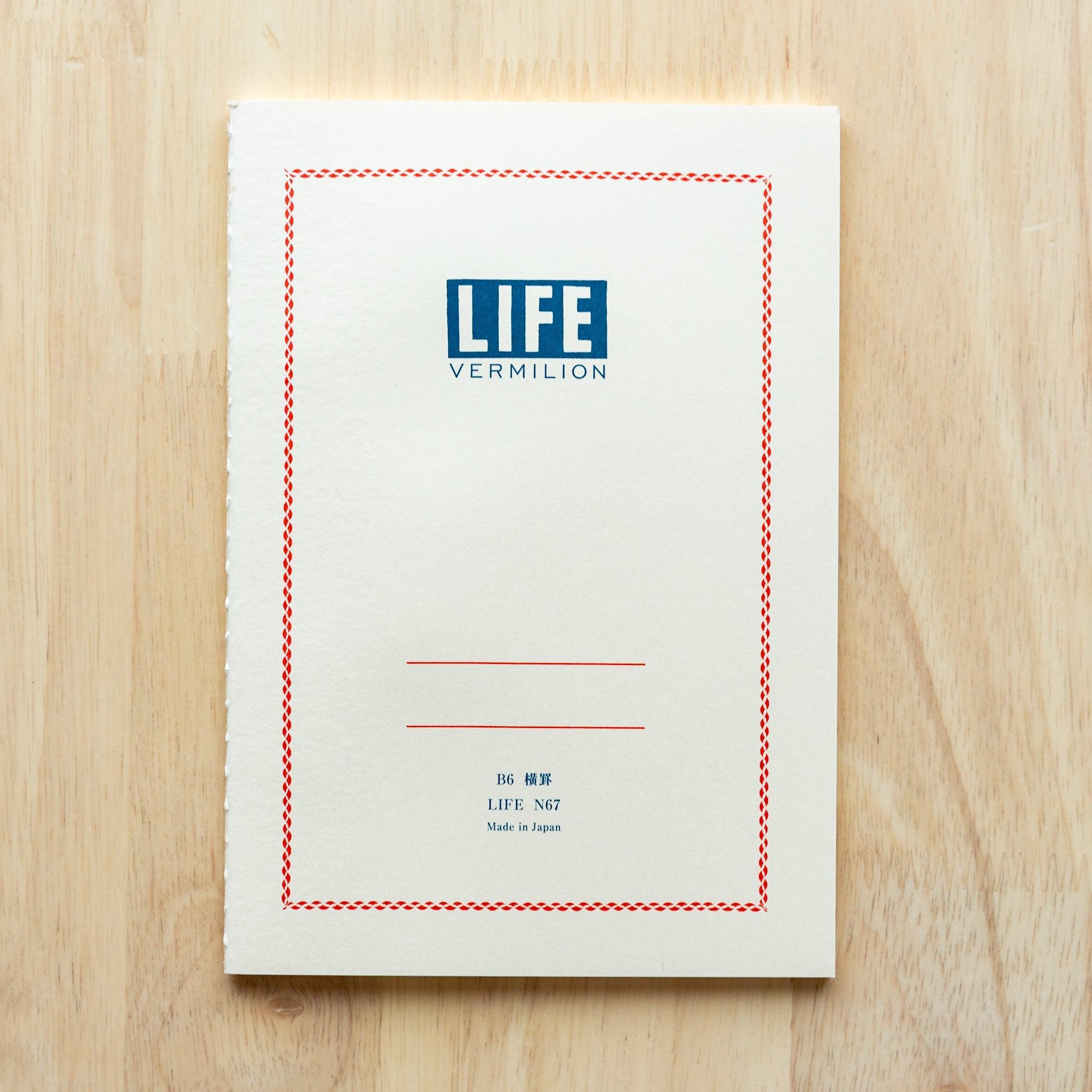 A single "LIFE Vermilion" notebook in A5 size with a beige cover, red logo, and minimal border design, displayed on a wooden surface.