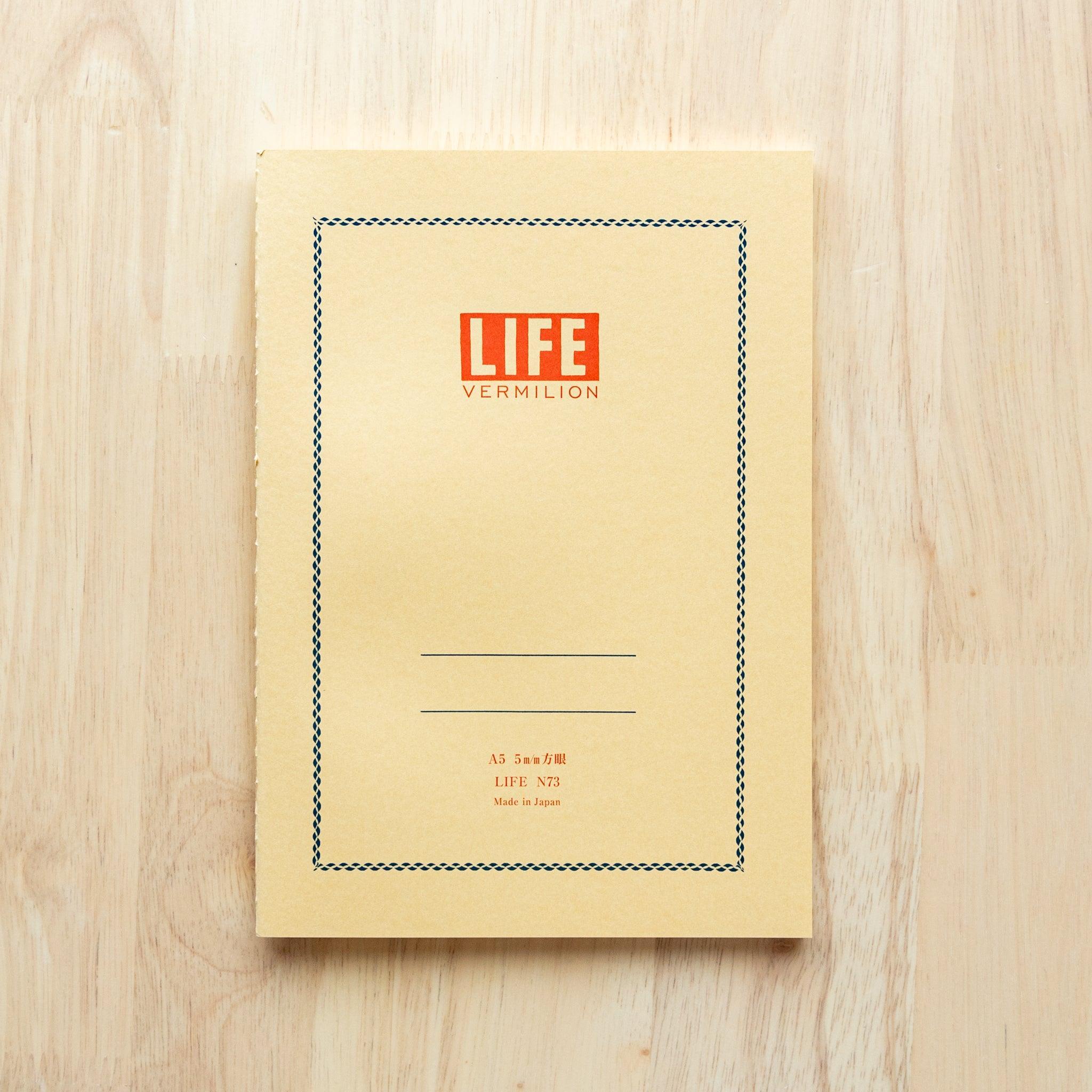 A single "LIFE Vermilion" notebook in A5 size with a beige cover, red logo, and minimal border design, displayed on a wooden surface.