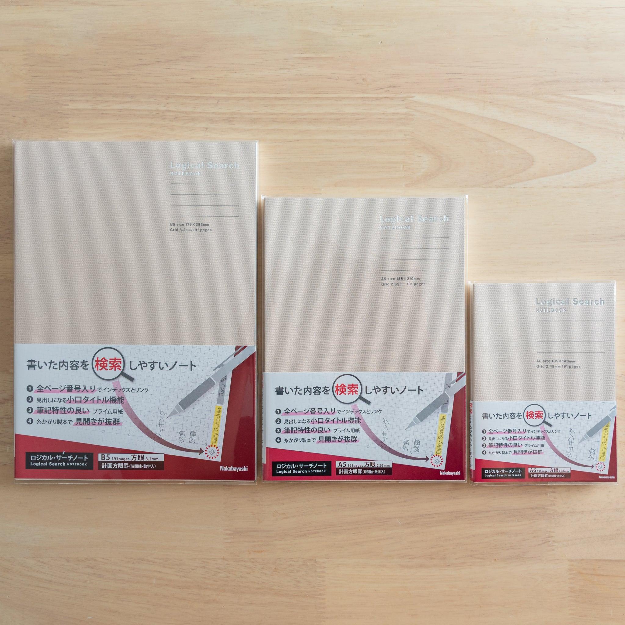 Three Japanese "Logical Search" notebooks with beige covers in different sizes, sealed in plastic, placed on a wooden surface.