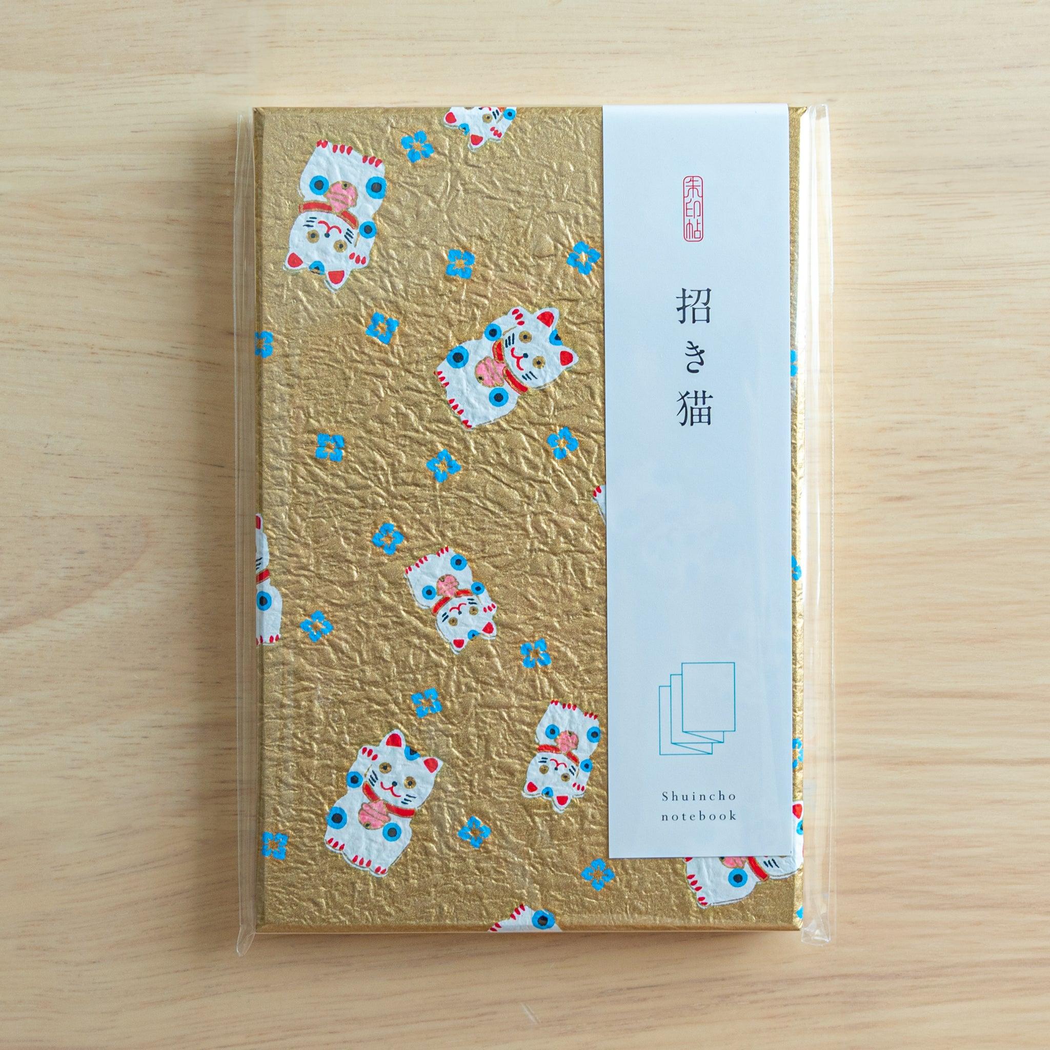 Japanese Goshuinsho stamp book in packaging, gold washi cover with lucky cat and blue flowers, ideal Japanese stationery