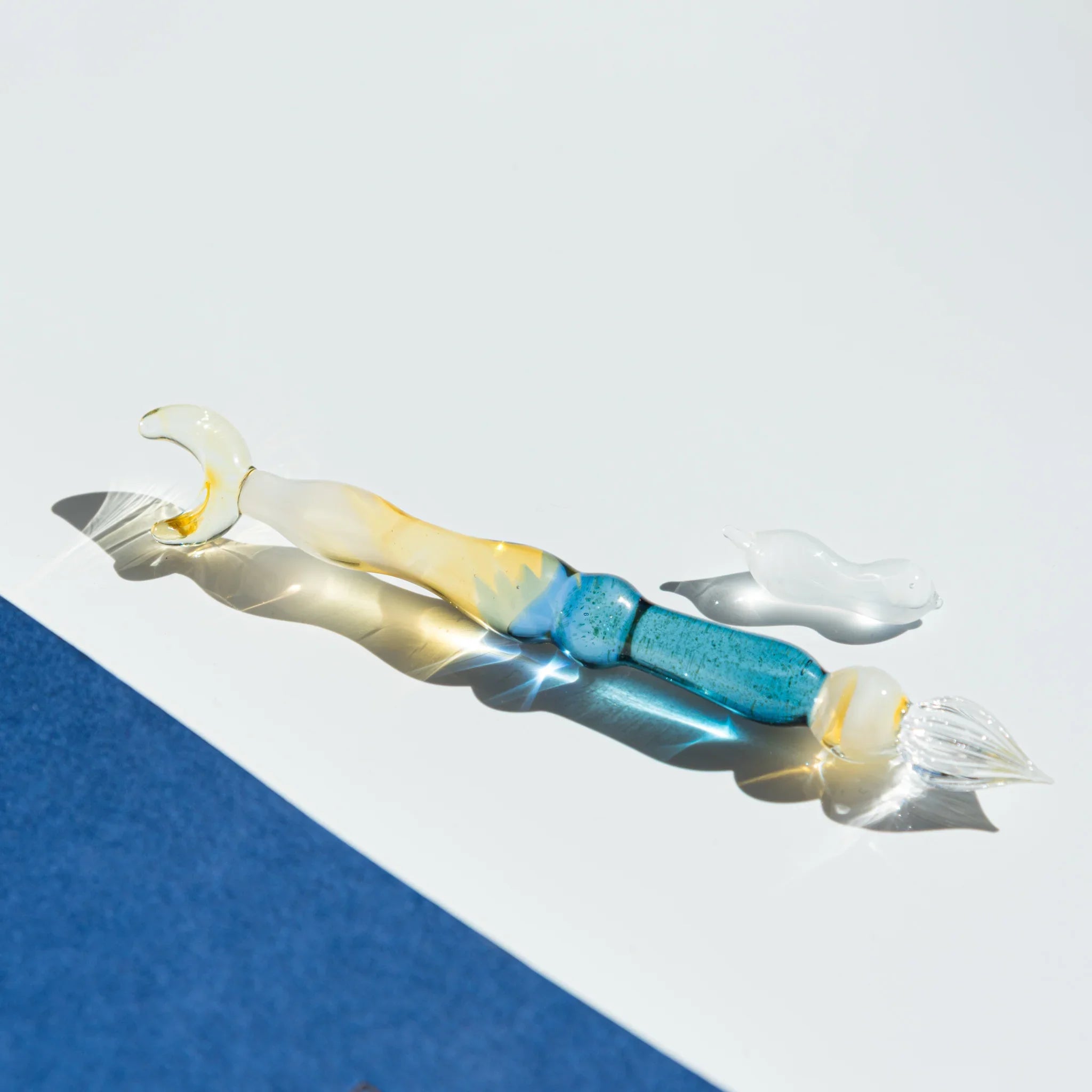 Lunar Glow glass dip pen with pale yellow iridescent barrel, turquoise wrapped handle, and moon-shaped pen rest