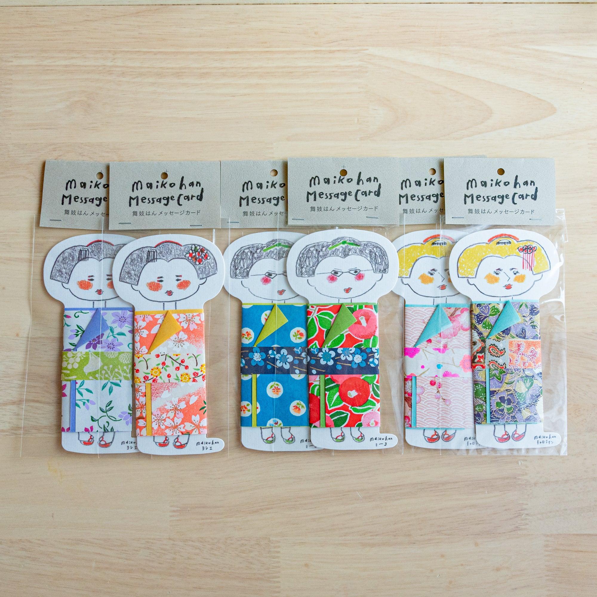 Six packaged Maikohan Message Card sets on wood, each a maiko die-cut card with a distinct yuzen washi kimono pattern