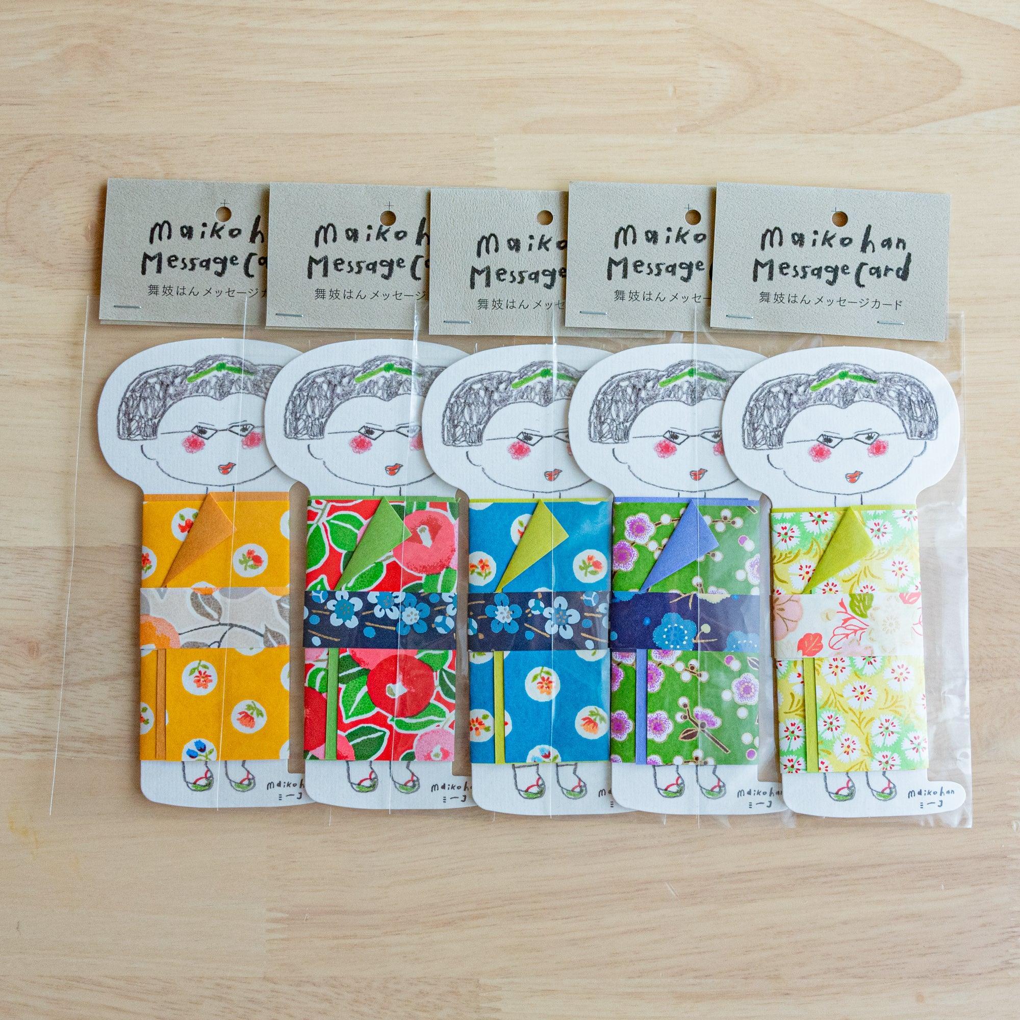 Five Maikohan Message Card packages on wood, each with a gray-haired maiko figure in a different yuzen washi kimono pattern