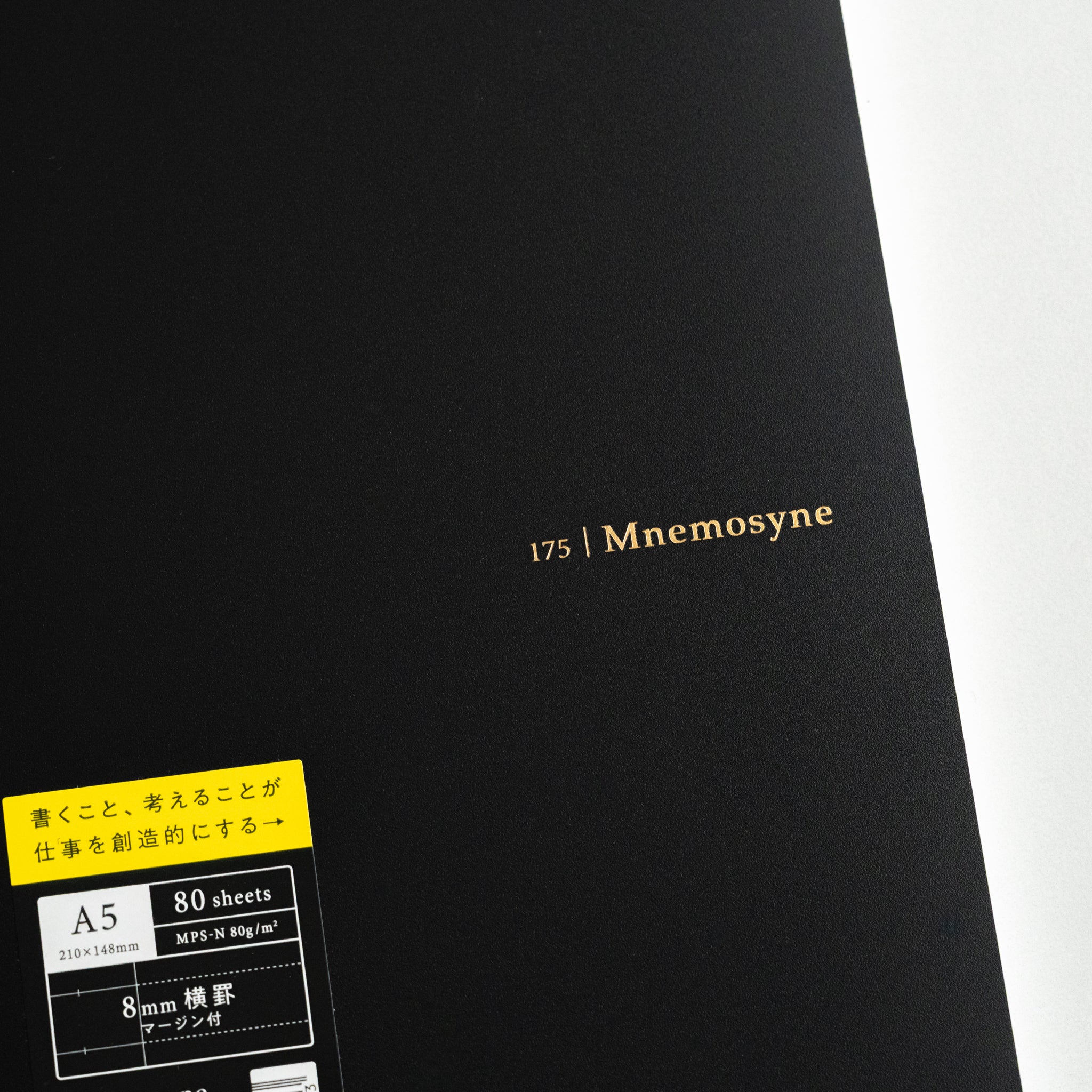 Black cover of Maruman Mnemosyne lined notebook featuring elegant gold Mnemosyne logo and yellow A5 product label, minimalist Japanese design.