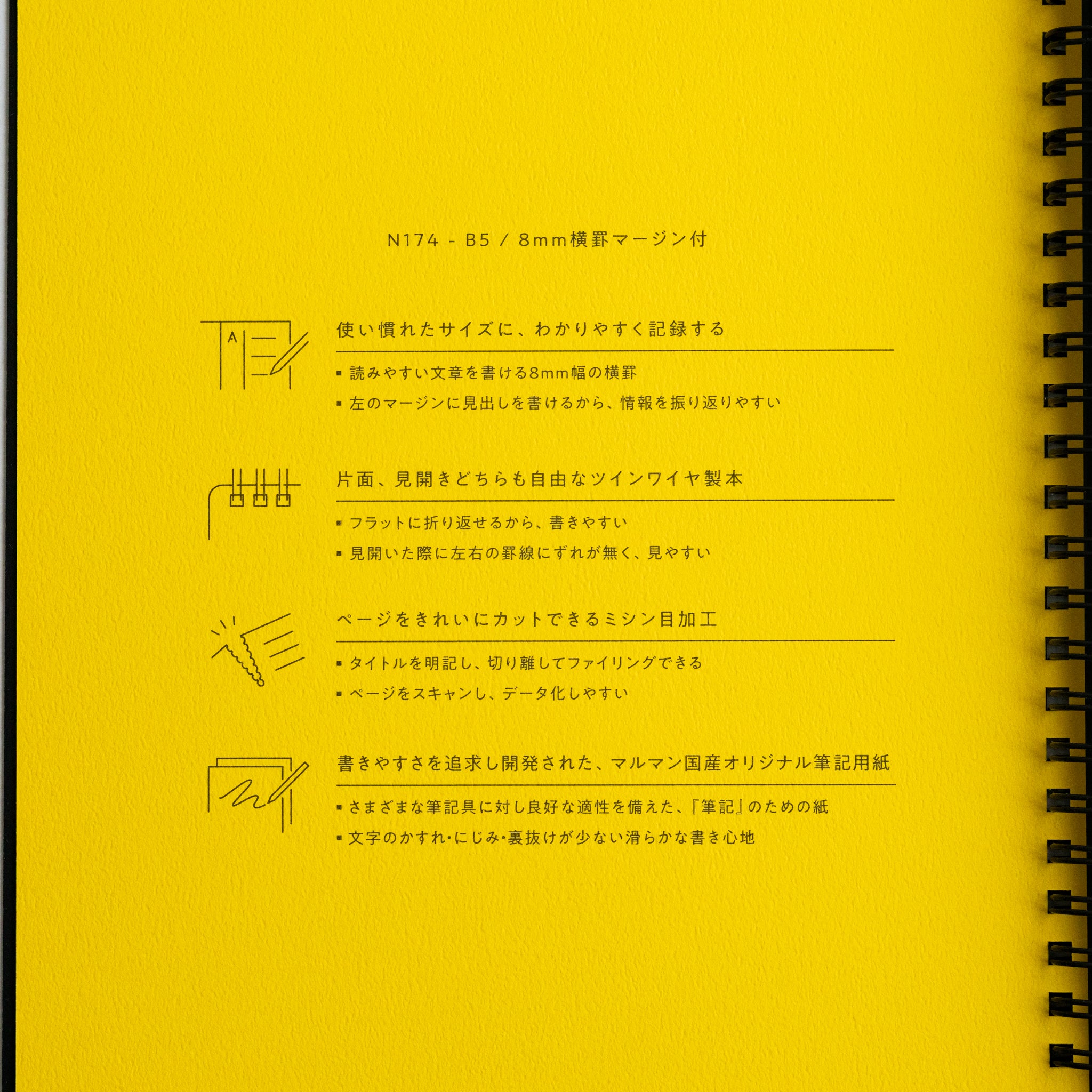 Yellow page of Maruman Mnemosyne notebook with black twin-ring binding and printed Japanese text and icons.