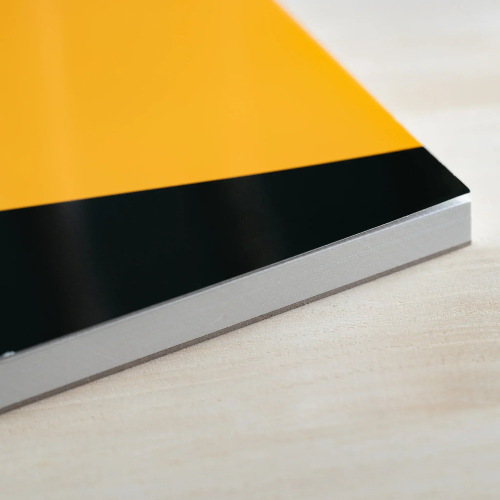 Close-up corner of a Maruman Japanese sketchbook with orange and black cover and thick white pages on a wooden surface.